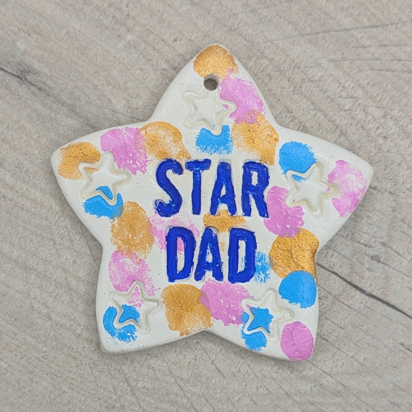 star dad stamped into clay star decoration, then painted in gold, pink and blue