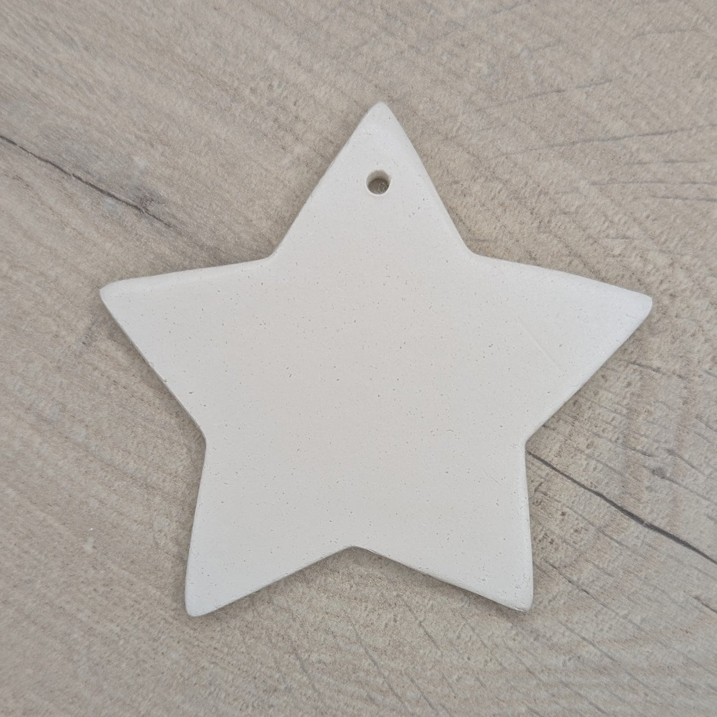 White 5 pointed star shaped clay decoration / ornament/ tag on a wooden background