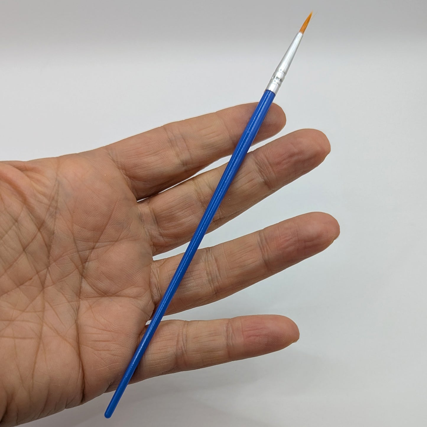 Hand holding a thin tip paintbrush