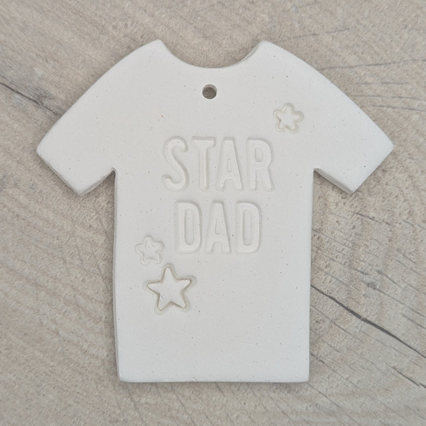 White clay t-shirt-shaped ornament / decoration with 'Star Dad' and small stars stamped into the clay