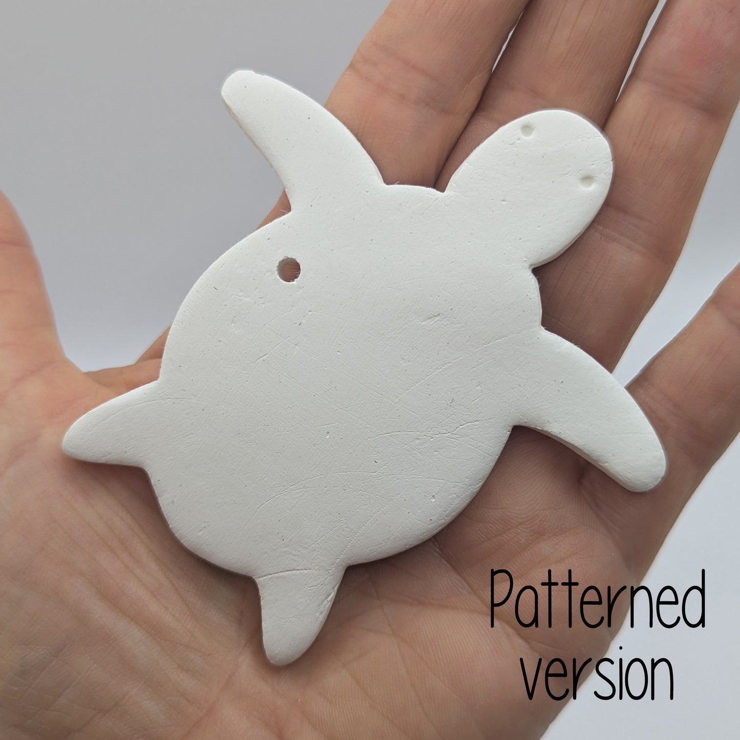 clay shaped turtle decoration in some ones hand to show scale