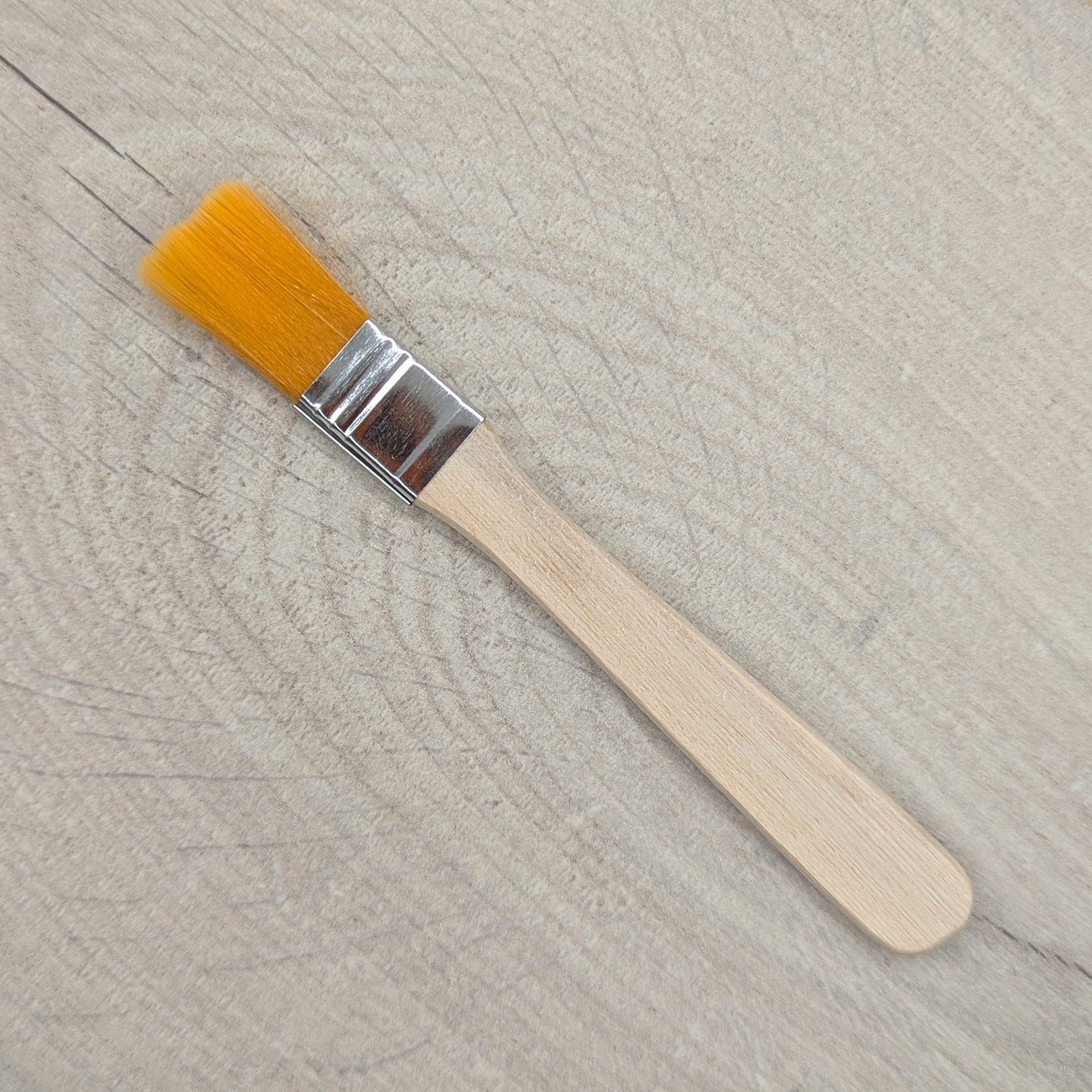 Paintbrush with yellow bristles and a wooden handle