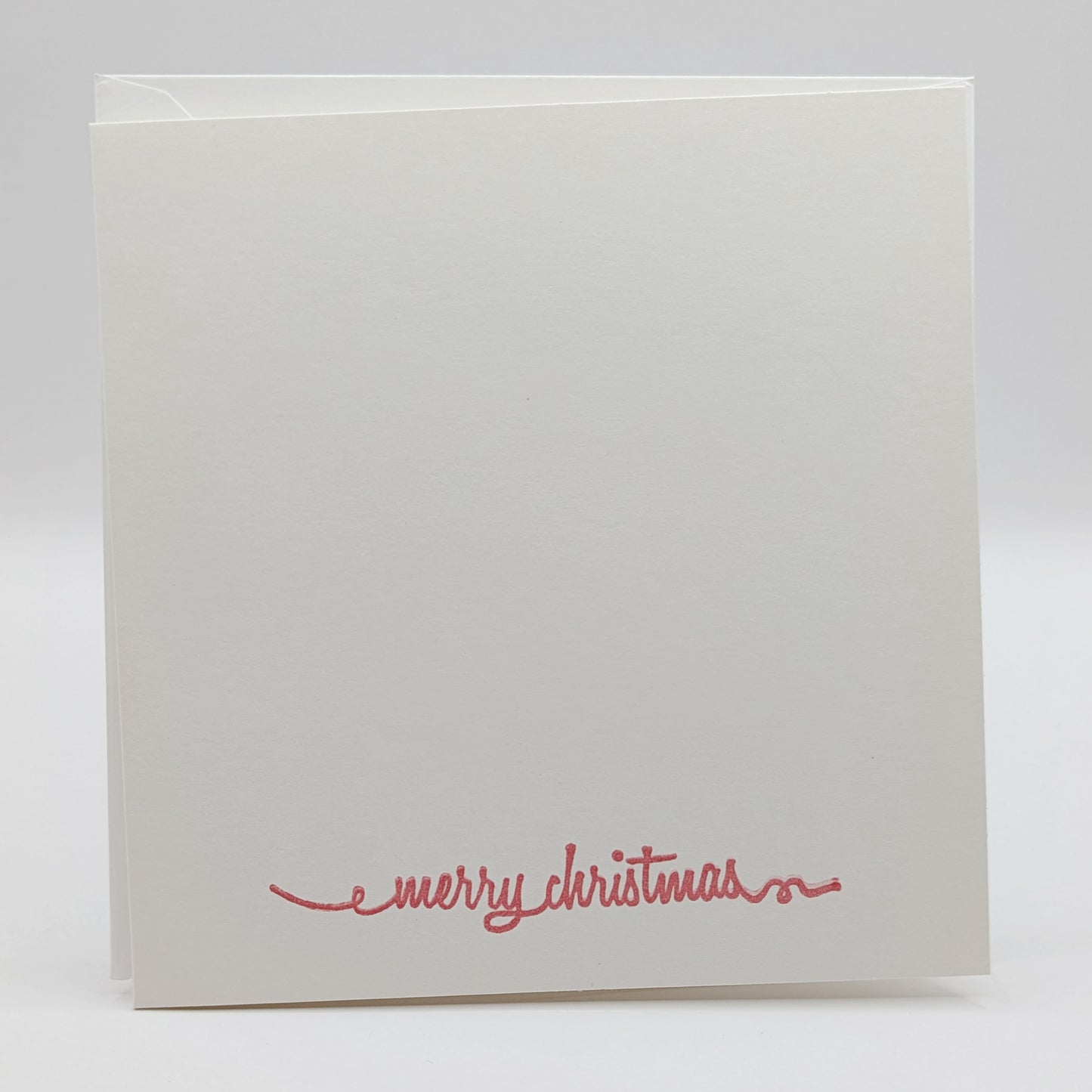 merry Christmas in a script font, stamped in red ink onto a white card comes with matching envelope