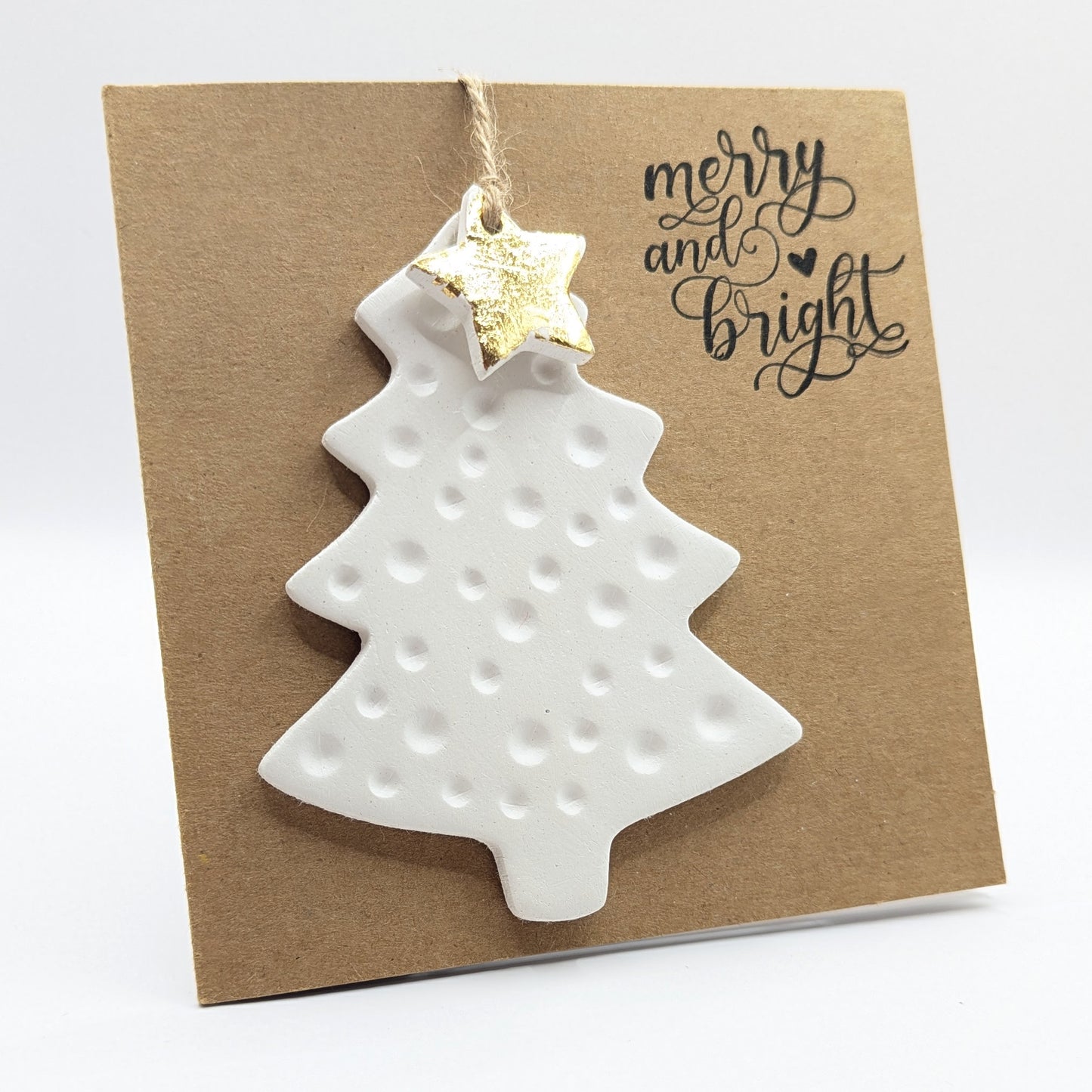 White clay Christmas tree ornament with gold star on a 'merry and bright' kraft coloued card