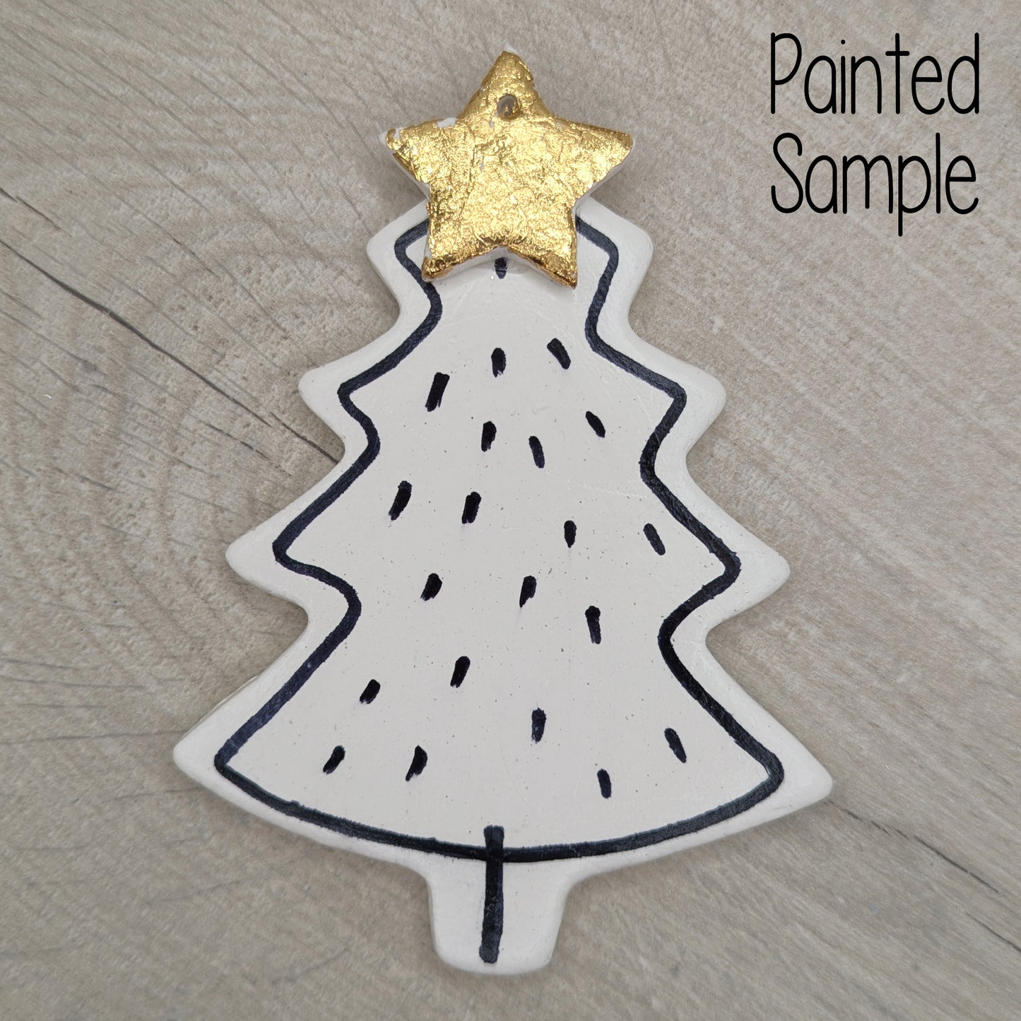 Christmas tree shaped decoration, with a simple black pen outline around the edge of the shape with a gold foil star on top