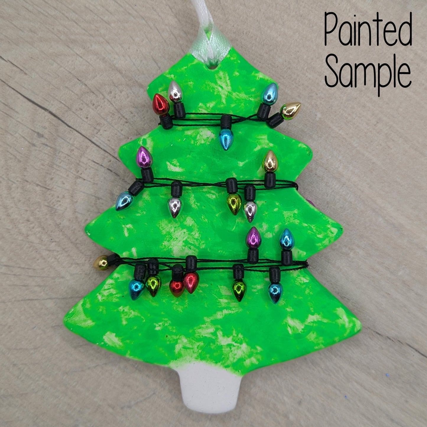 Decorative Christmas tree ornament painted in a bright green with colorful mini xmas lights wrapped around it