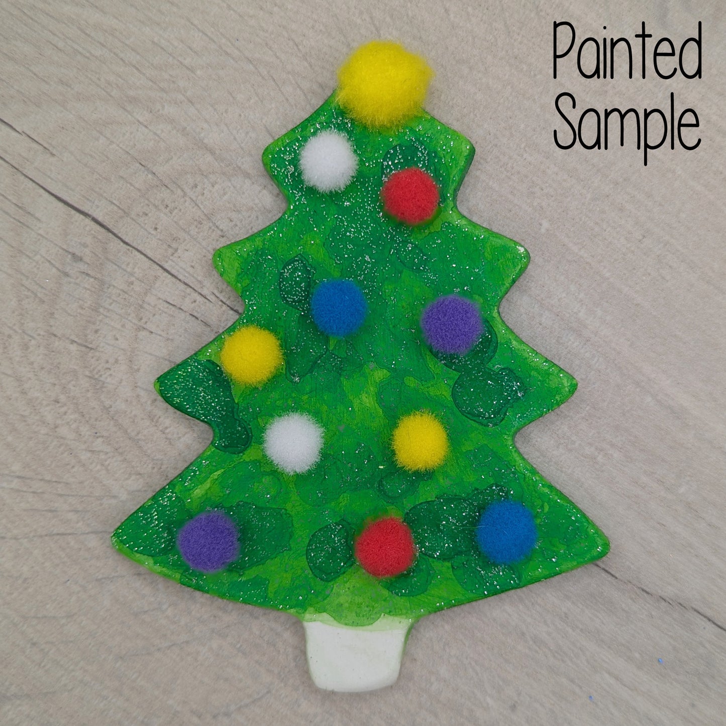 sample of painted and decoratede Christmas tree ornament / decoration decorated with colorful pom-poms and glitter green paint