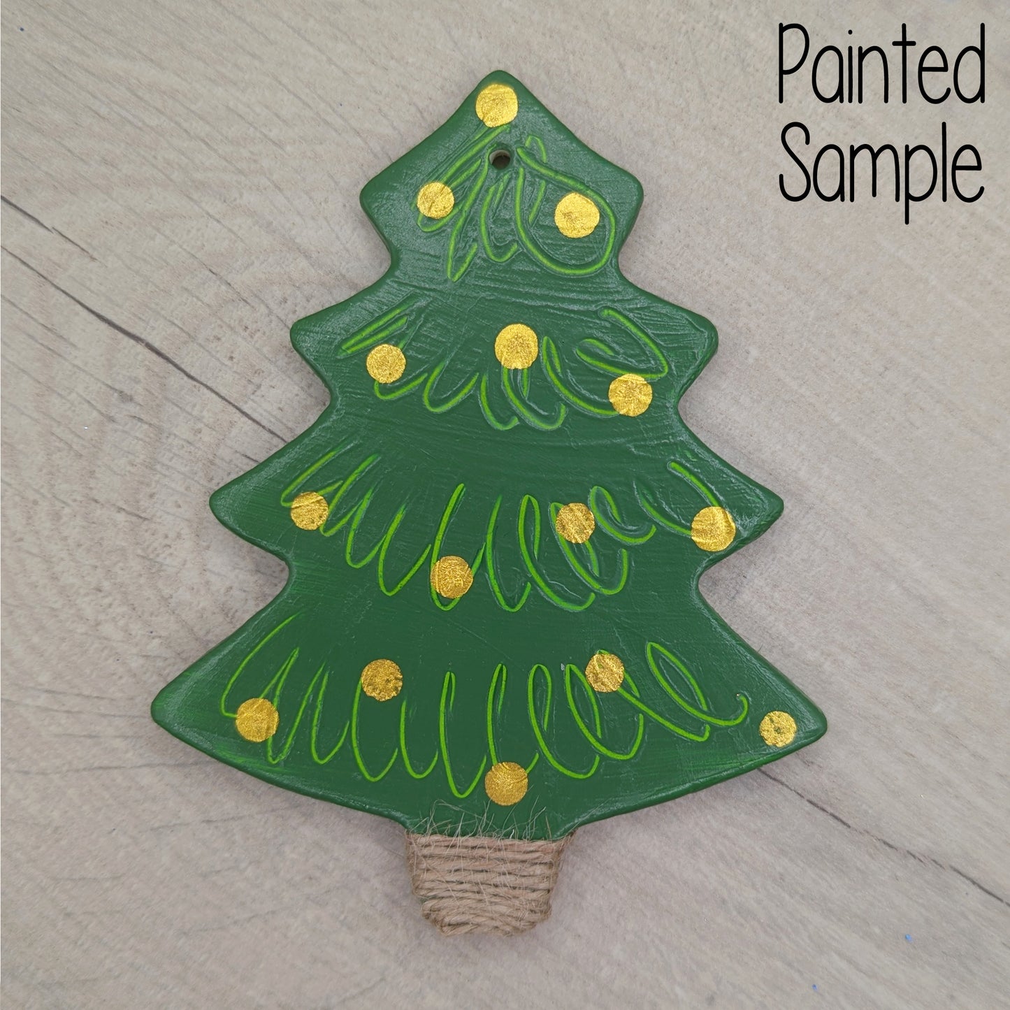 Green painted clay Christmas tree decoration with gold dots to represent baubles and jute cord wrapped around the base/trunk