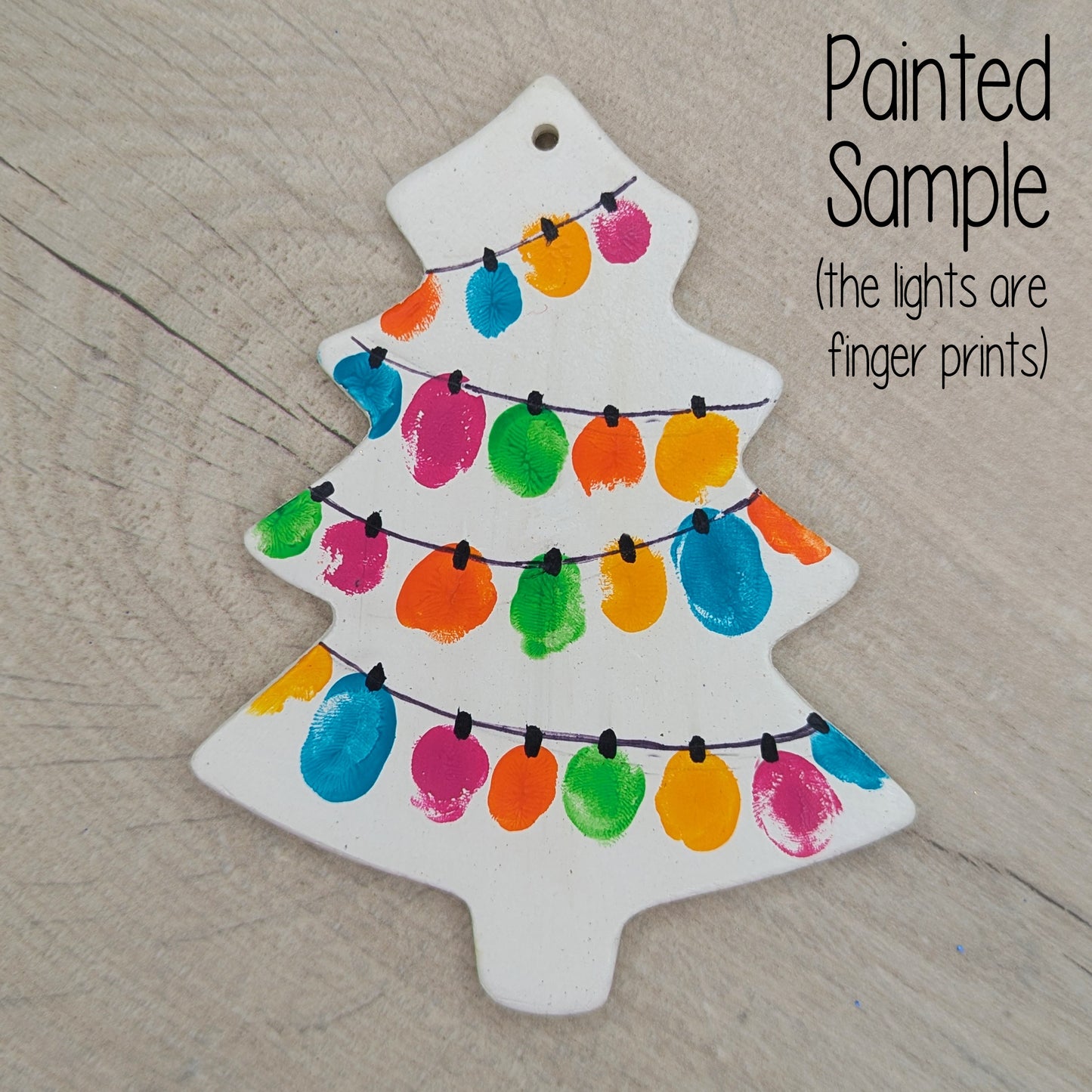 sample of painted Christmas tree decoration, made of white air dried clay and then painted using finger prints to look like fairy lights with a black pen line connecting them