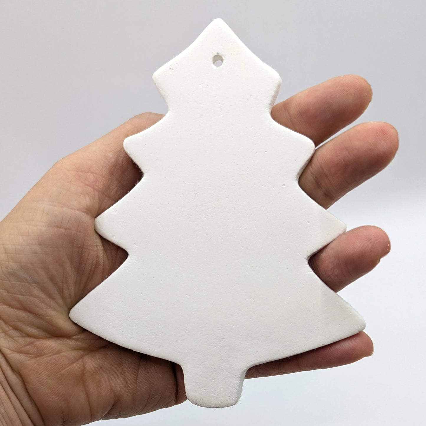 white air dried clay Christmas tree decoration shown in palm of hand, plain / pattern free design