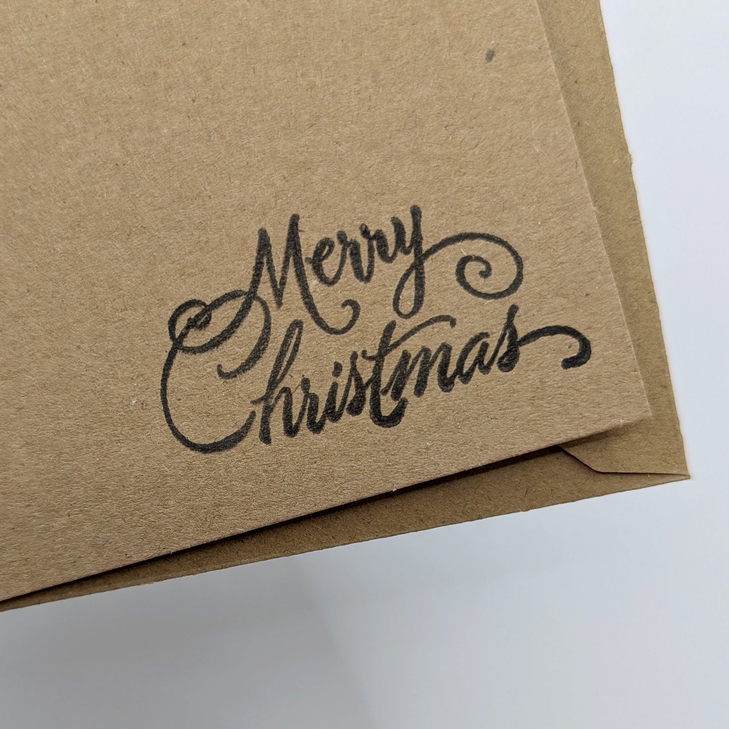 close up of merry Christmas, stamped in black ink onto a kraft card
