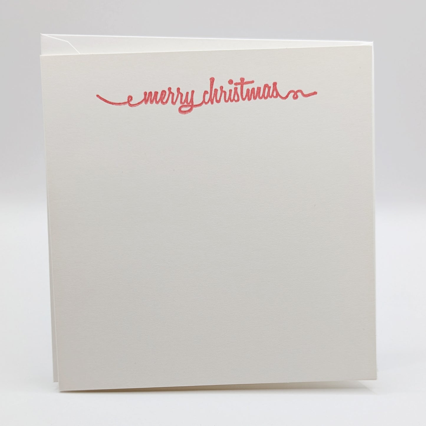 merry Christmas in a script font, stamped in red ink onto a white card comes with matching envelope