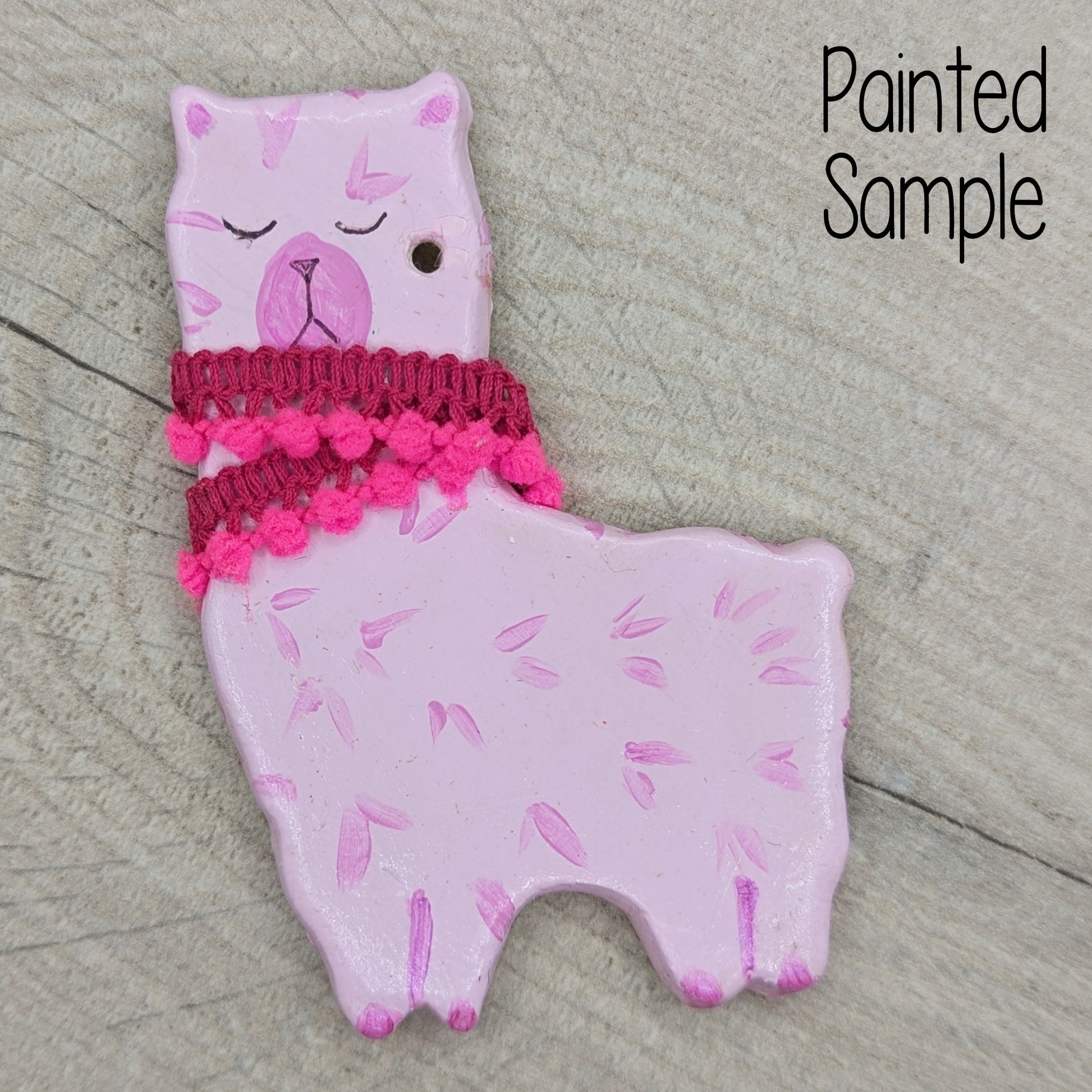 decoration sample of and alpaca or llarma painted in pinks with material pink trim around the neck 