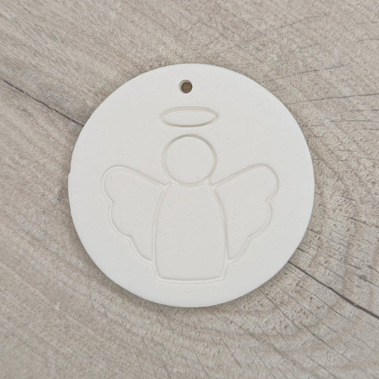 White clay disc with a simple clean angel design stamped onto it, hanging hole in the top, shown on a wooden background
