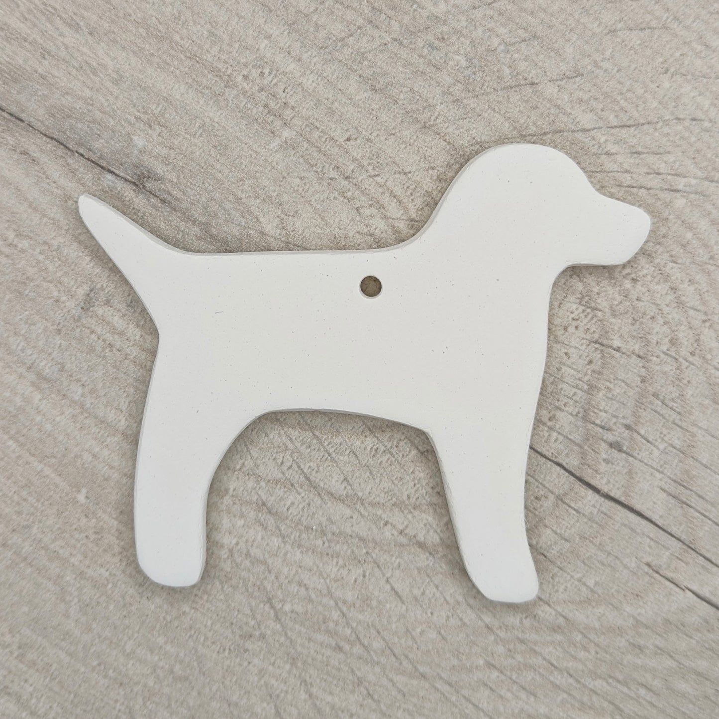 White air dried clay dog-shaped ornament on a wooden surface