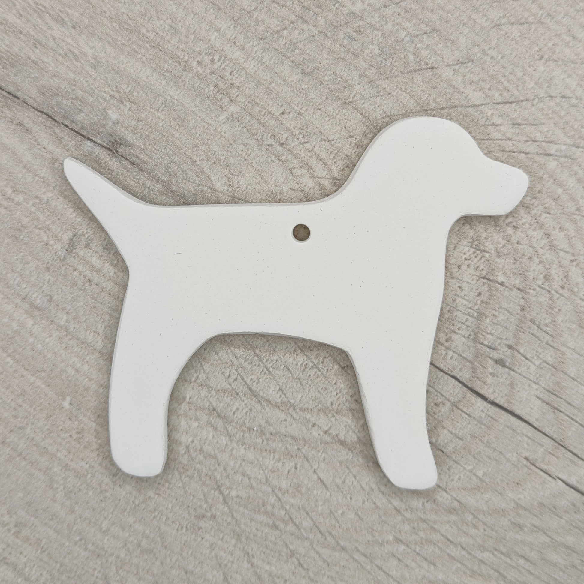White air dried clay dog-shaped ornament on a wooden surface