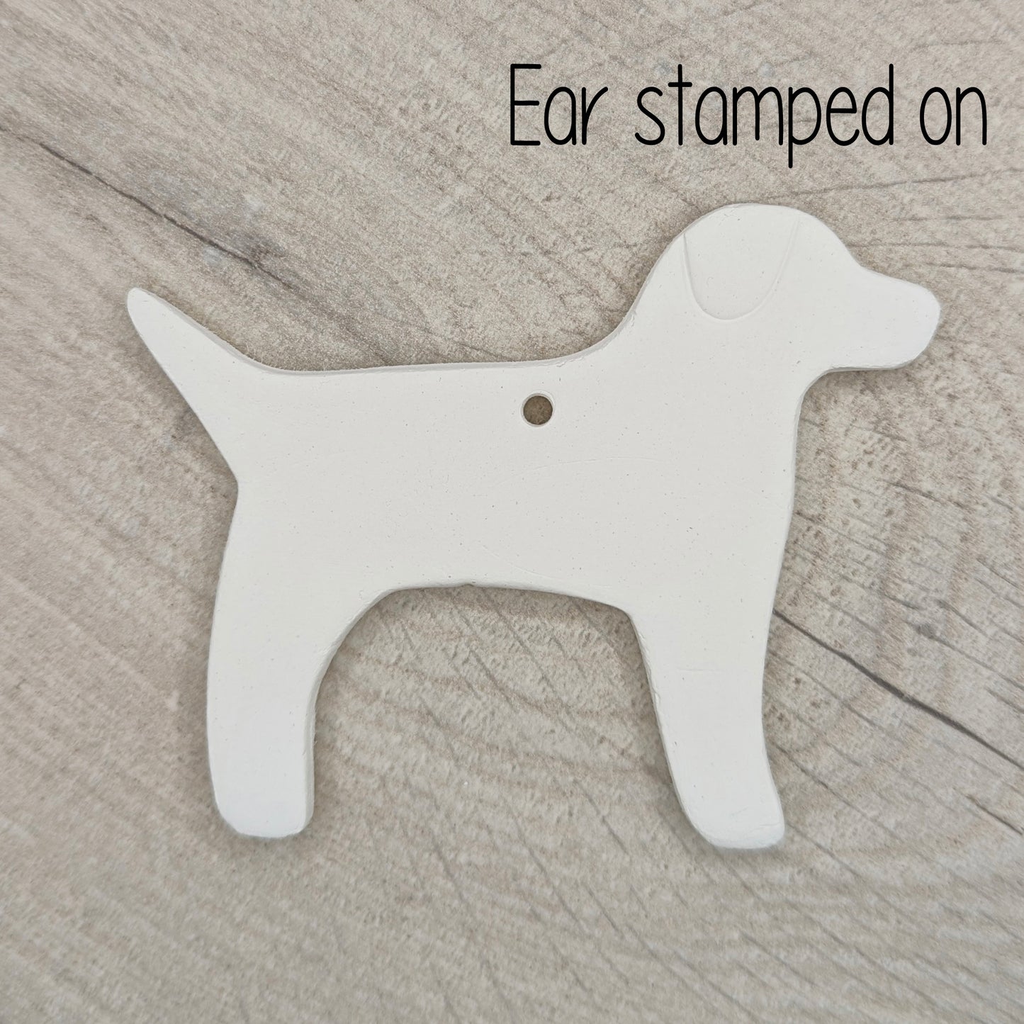 White air dried clay dog-shaped ornament on a wooden surface