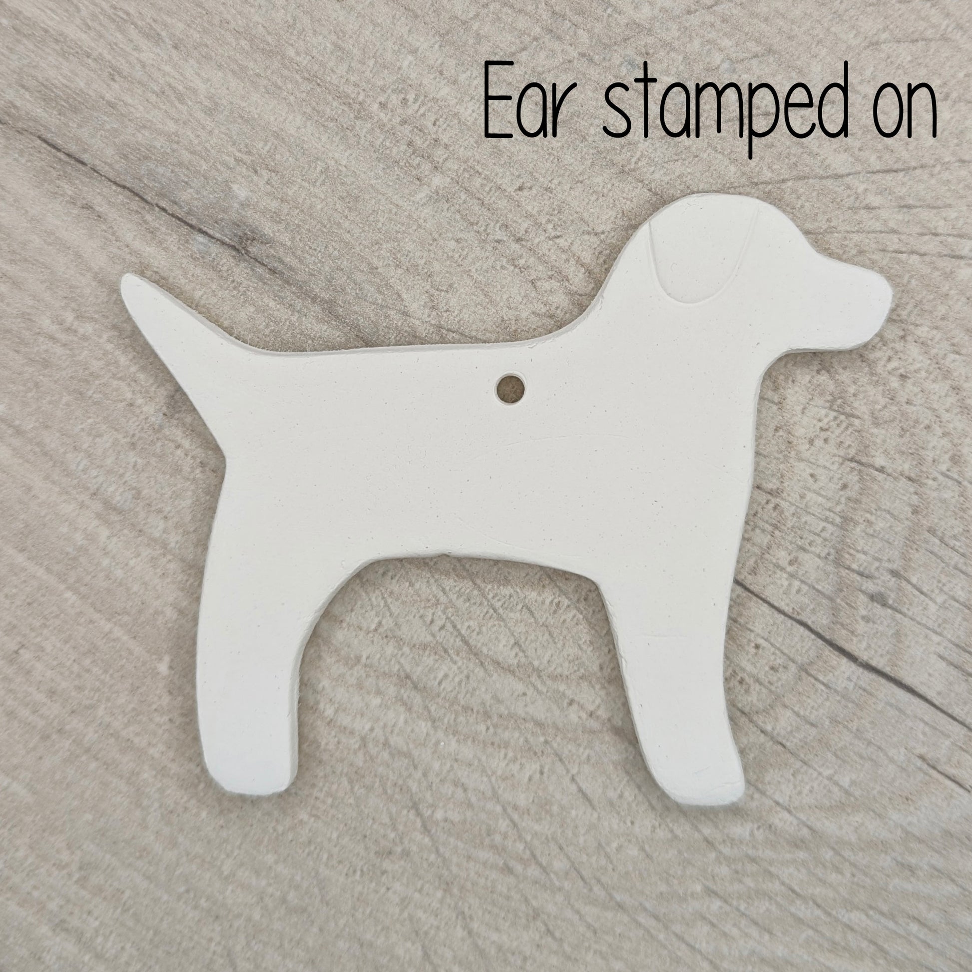 White air dried clay dog-shaped ornament on a wooden surface