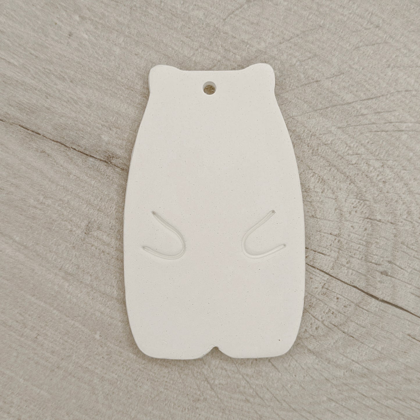 White clay abstract shaped bear on a wooden surface