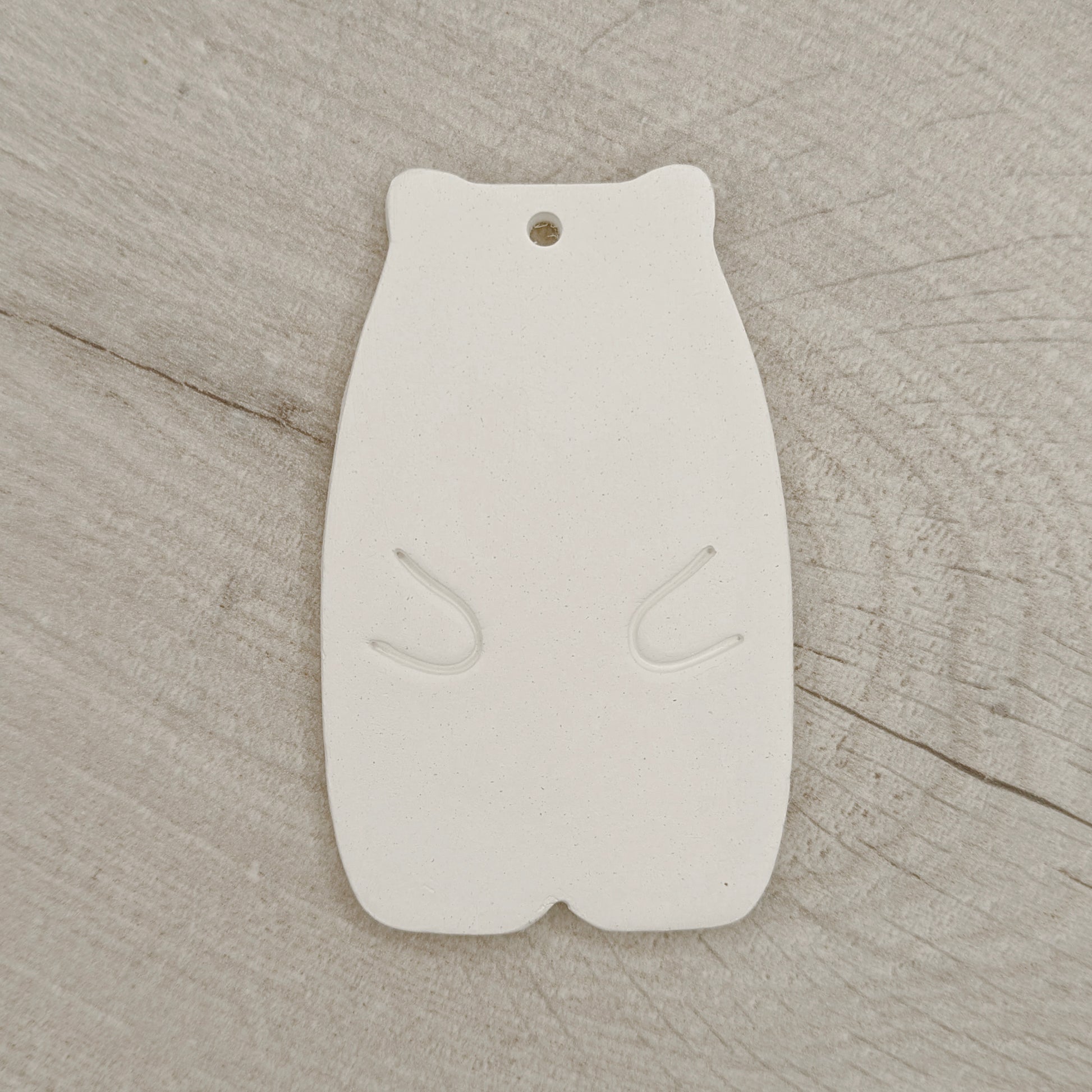 White clay abstract shaped bear on a wooden surface