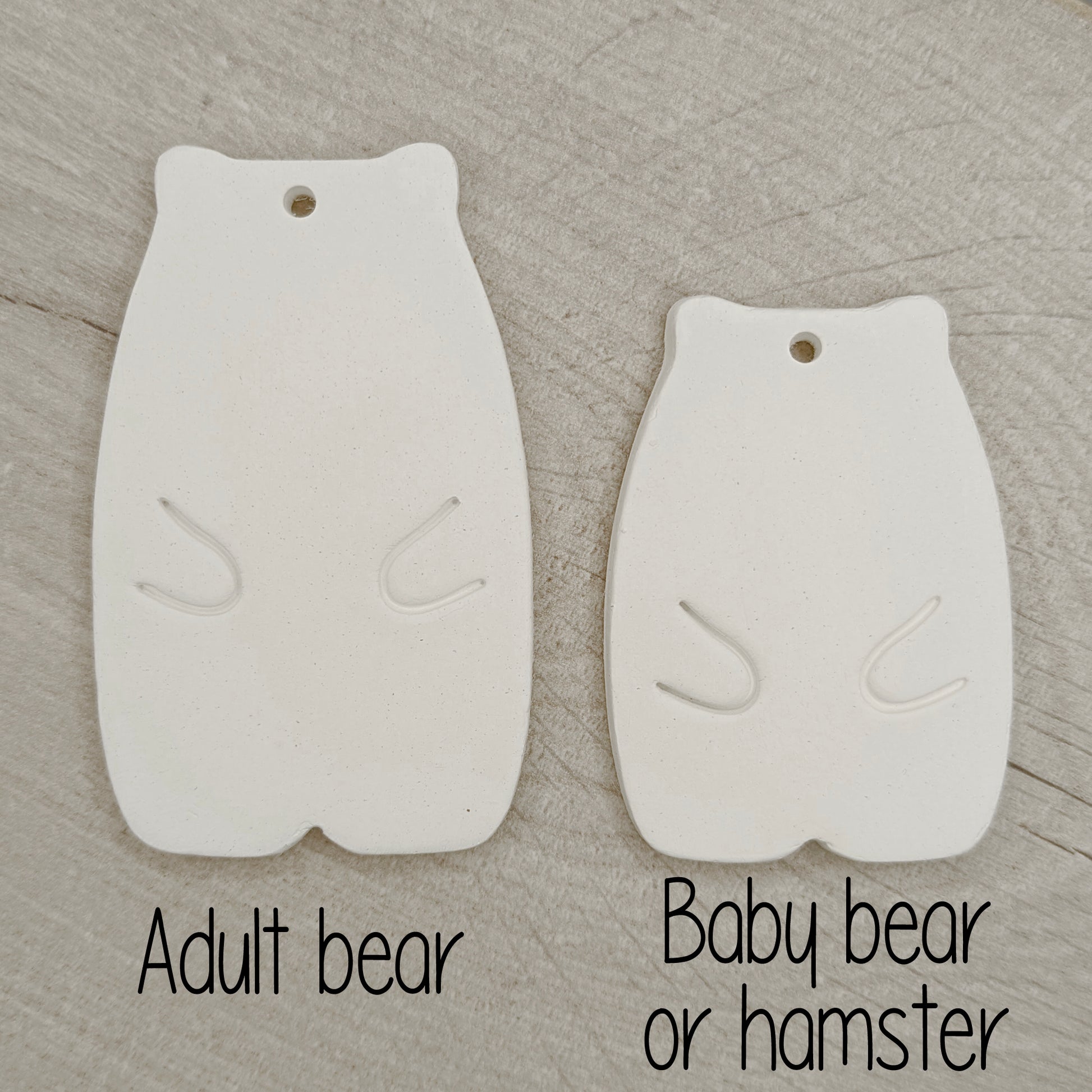 White clay abstract shaped bear  adult and baby size on a wooden surface