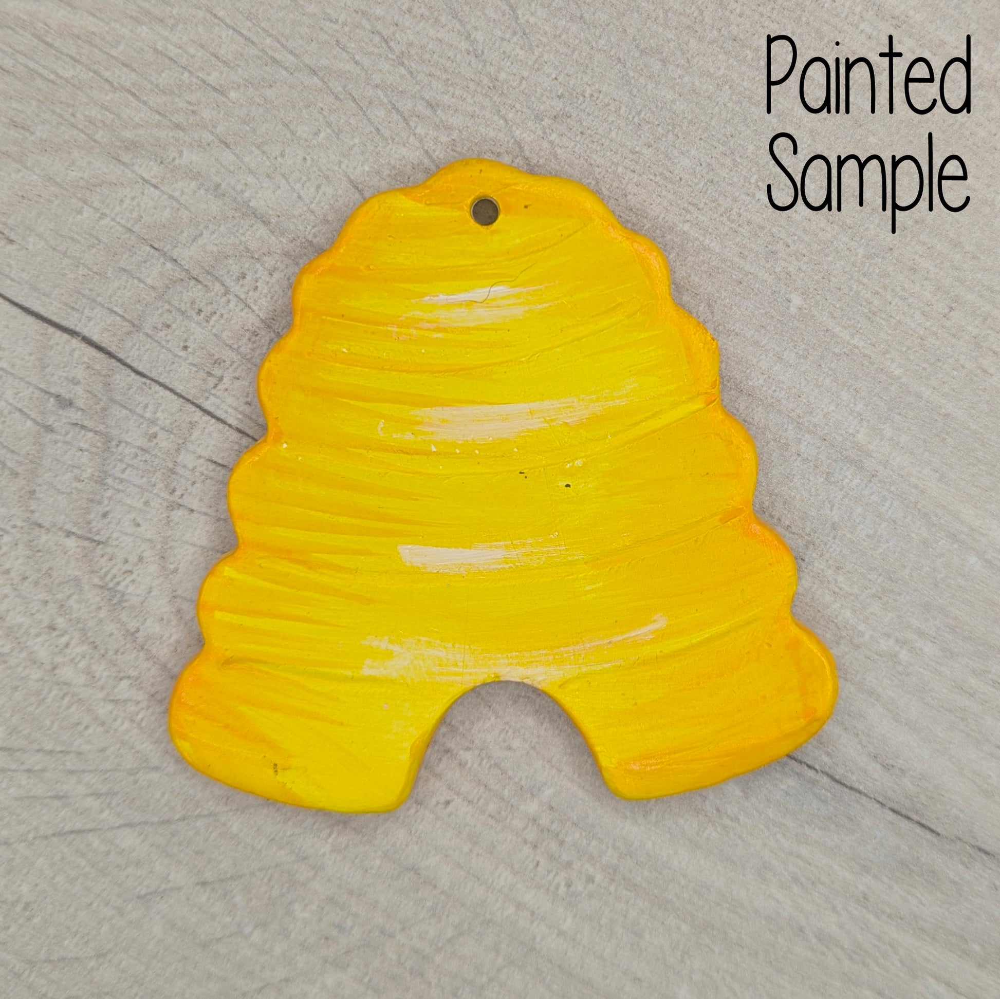 Yellow painted sample beehive clay decoration on a wooden surface with 'Painted Sample' text.