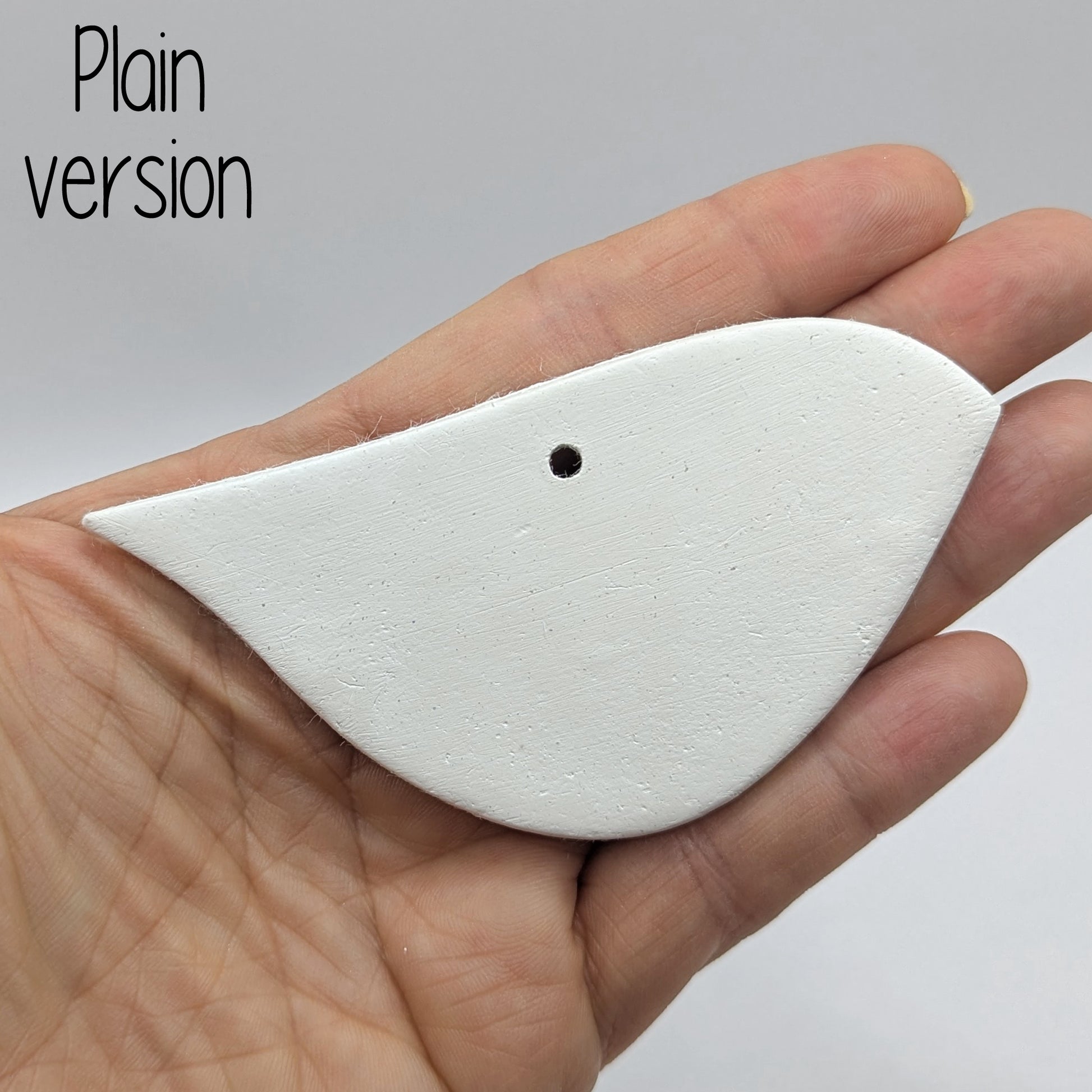 White clay abstract bird shaped clay decoration, held in hand to show scale