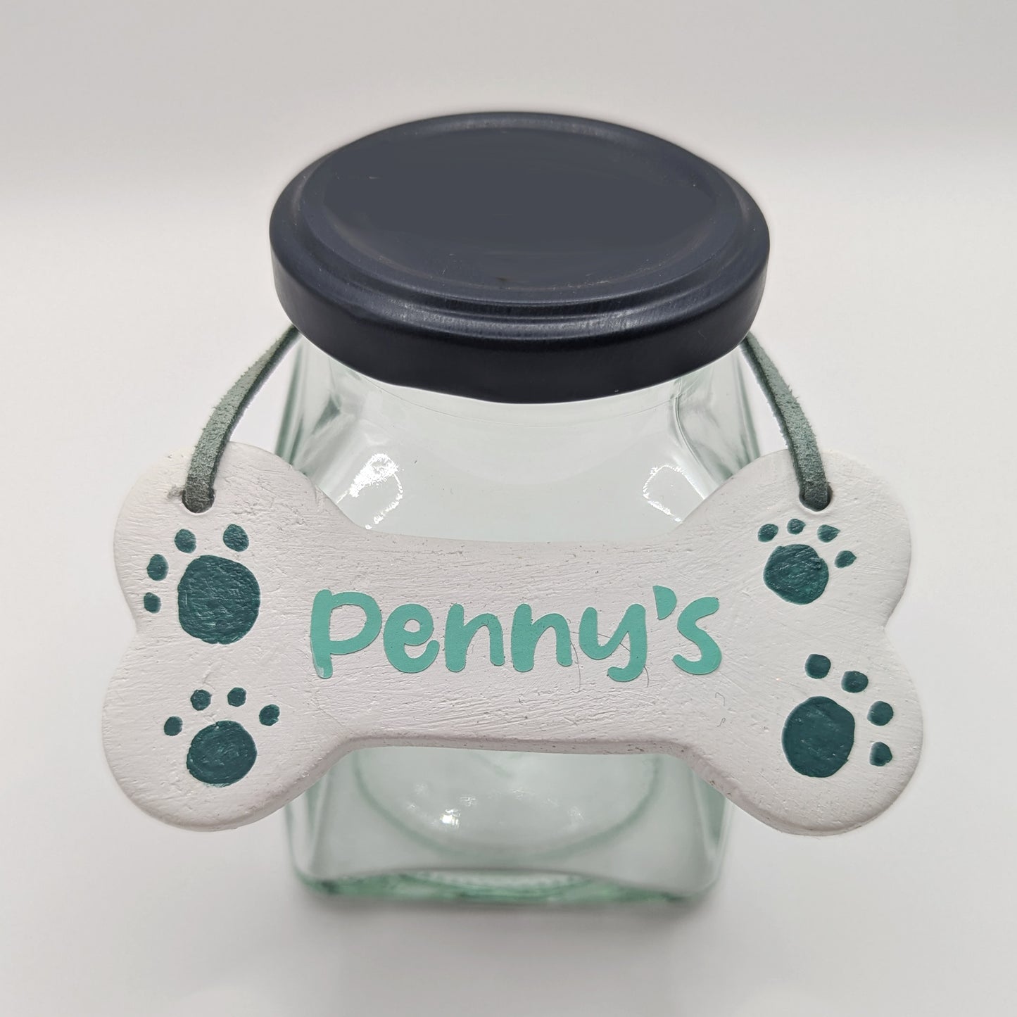 dog bone clay decoration displaved on a glass jar to show how it can be used, name on the bone decoration is Penny