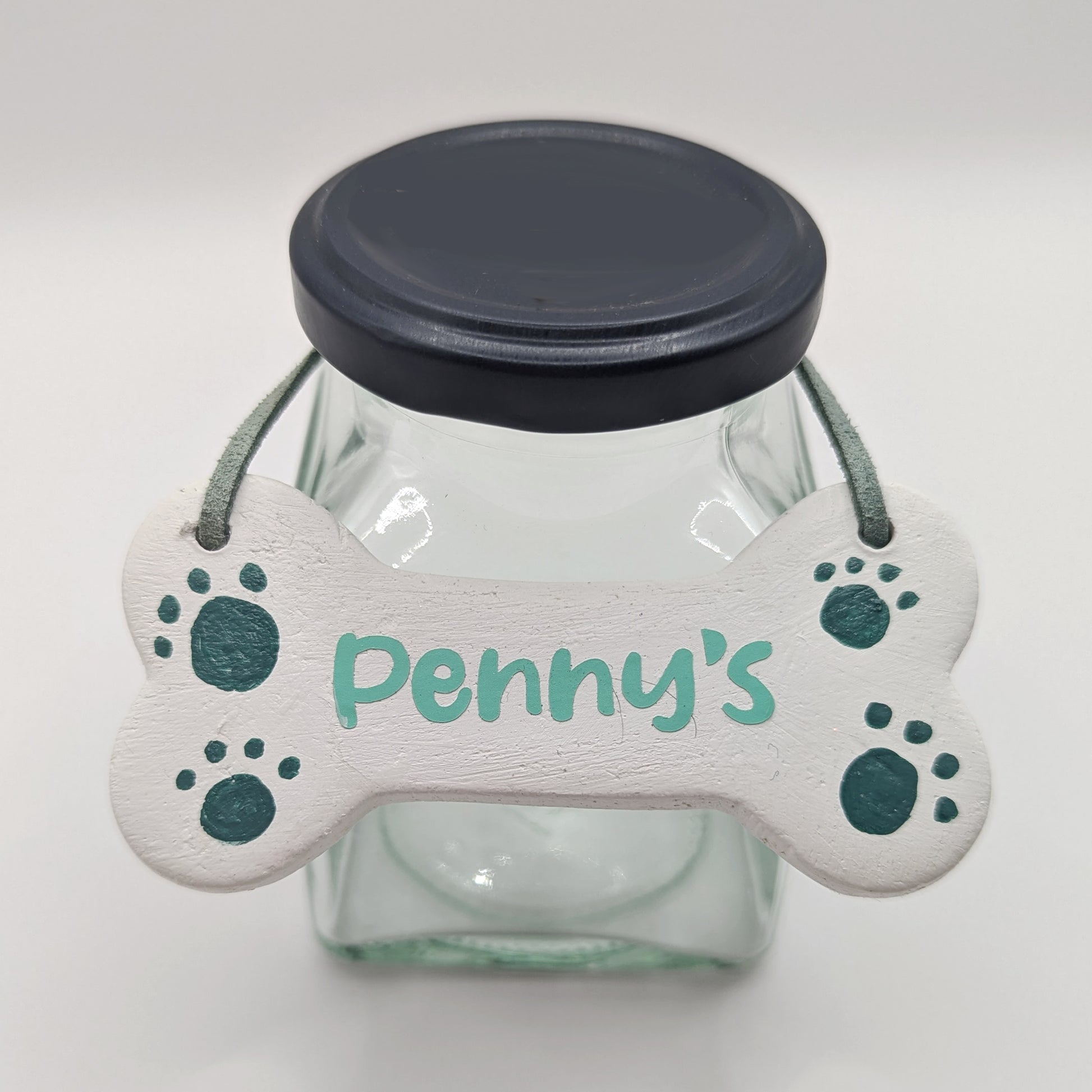 dog bone clay decoration displaved on a glass jar to show how it can be used, name on the bone decoration is Penny