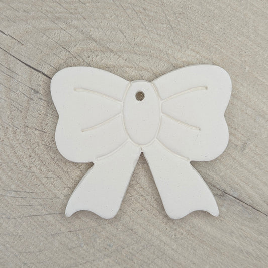 White bow-shaped clay decoration on a wooden surface