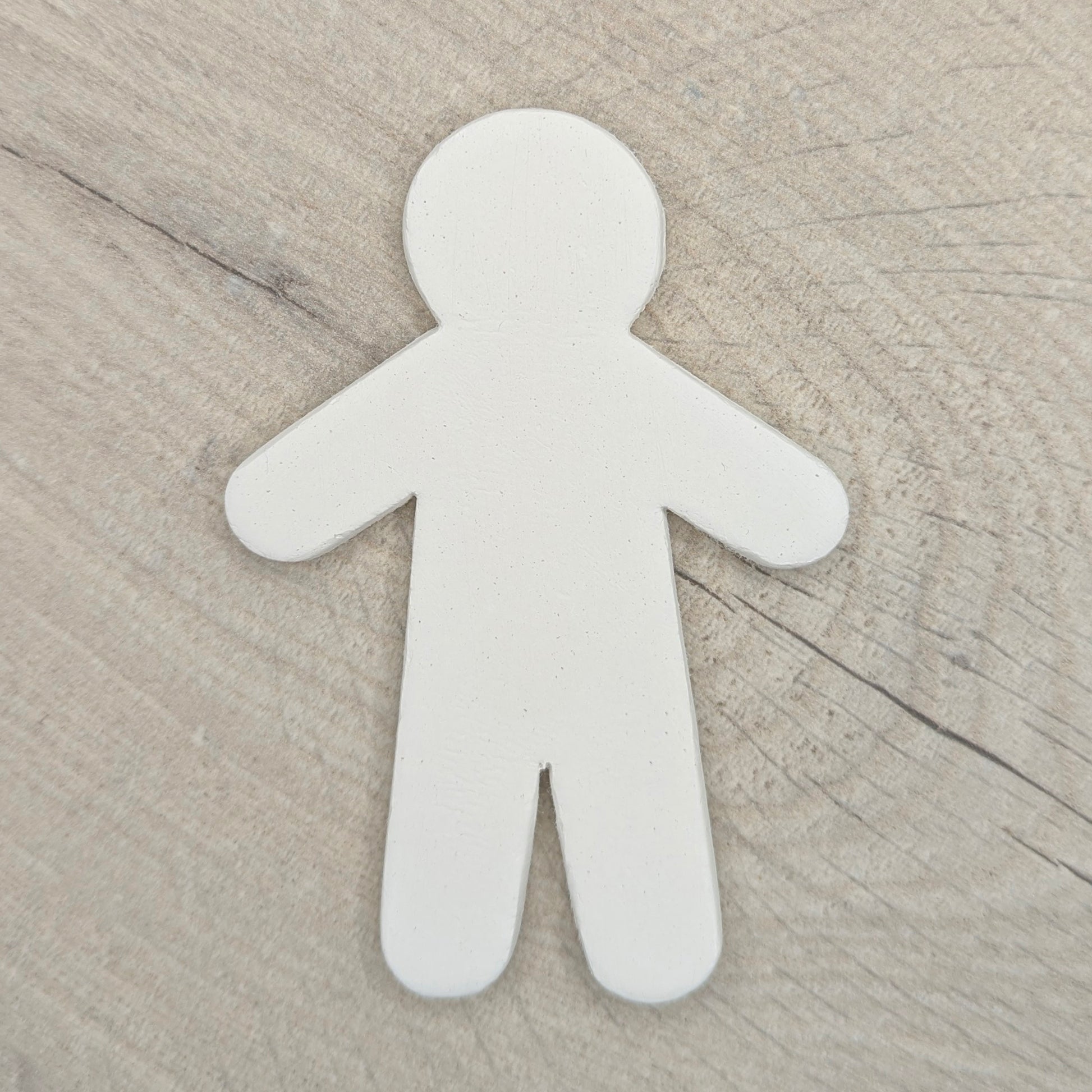 white air dried clay male shaped clay decoration on wooden background