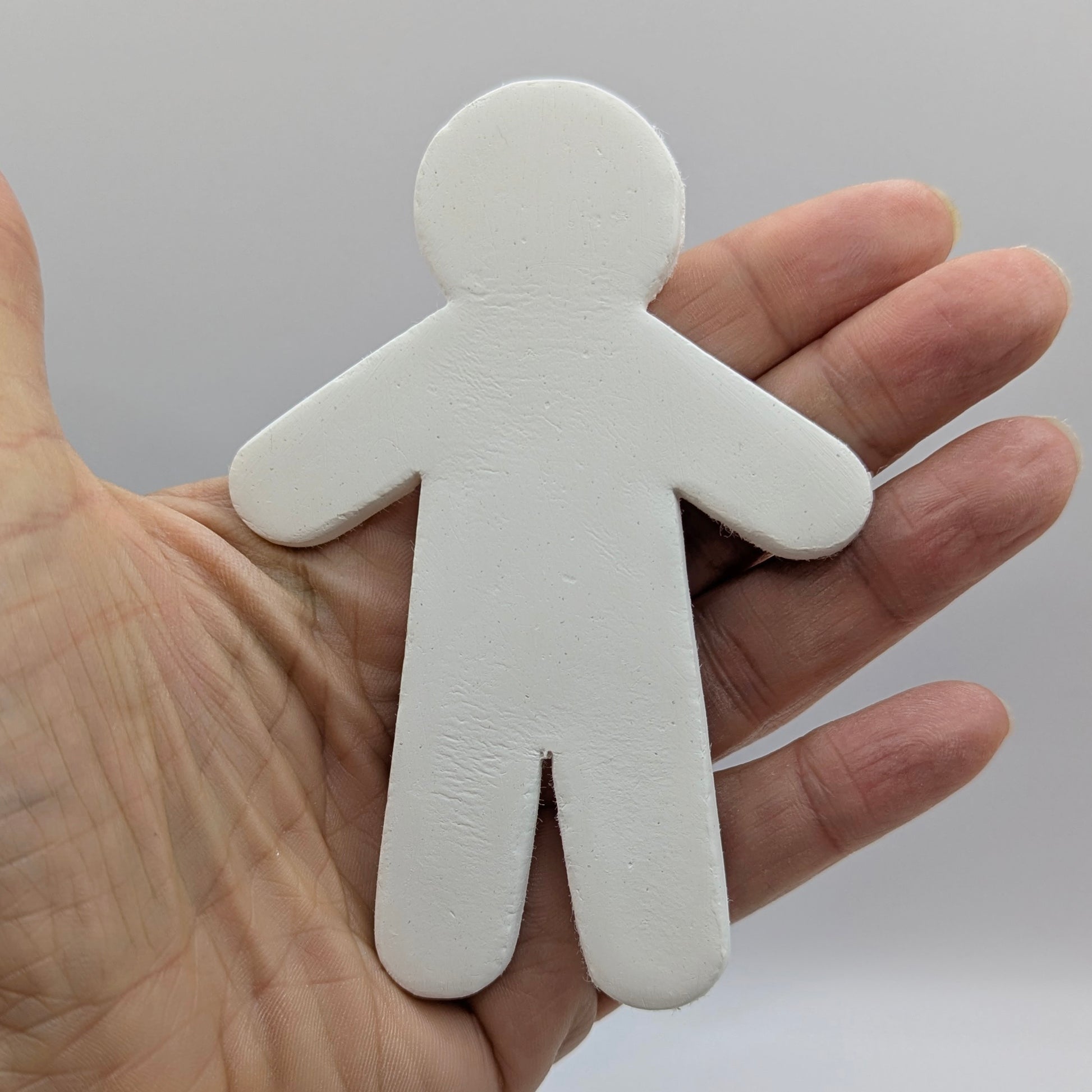 white air dried clay male shaped clay decoration been held in hand to show size