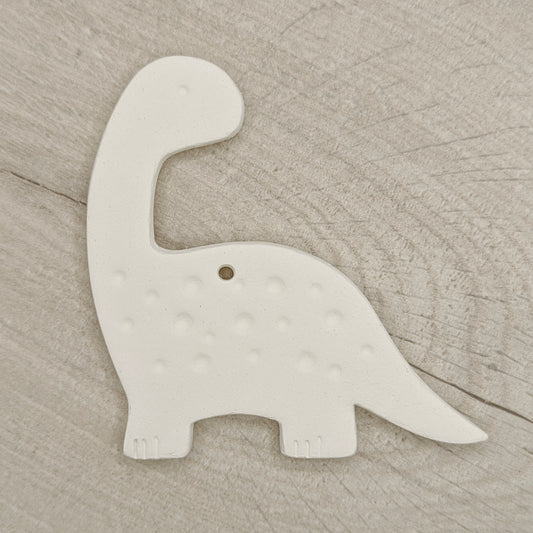 White clay diplodocus dinosaur-shaped decoration on a wooden surface