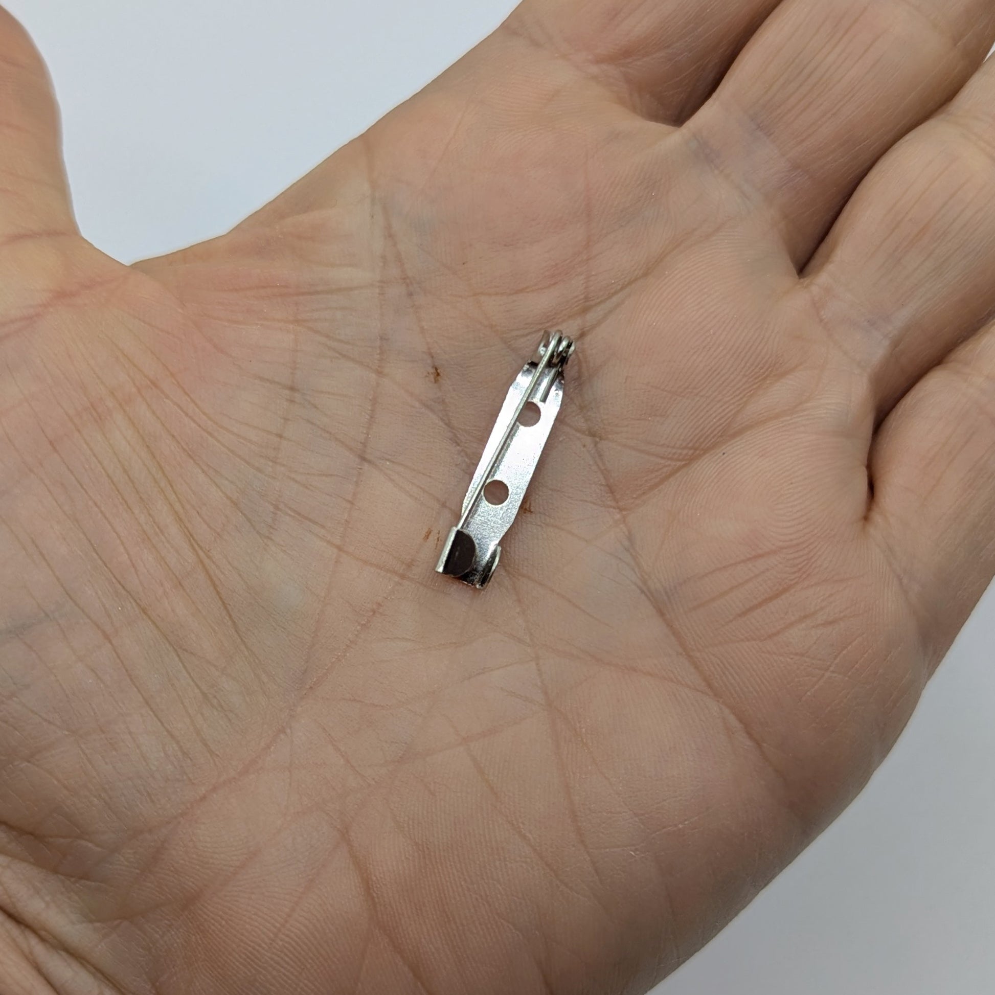 small metallic brooch clip on a person's palm 
