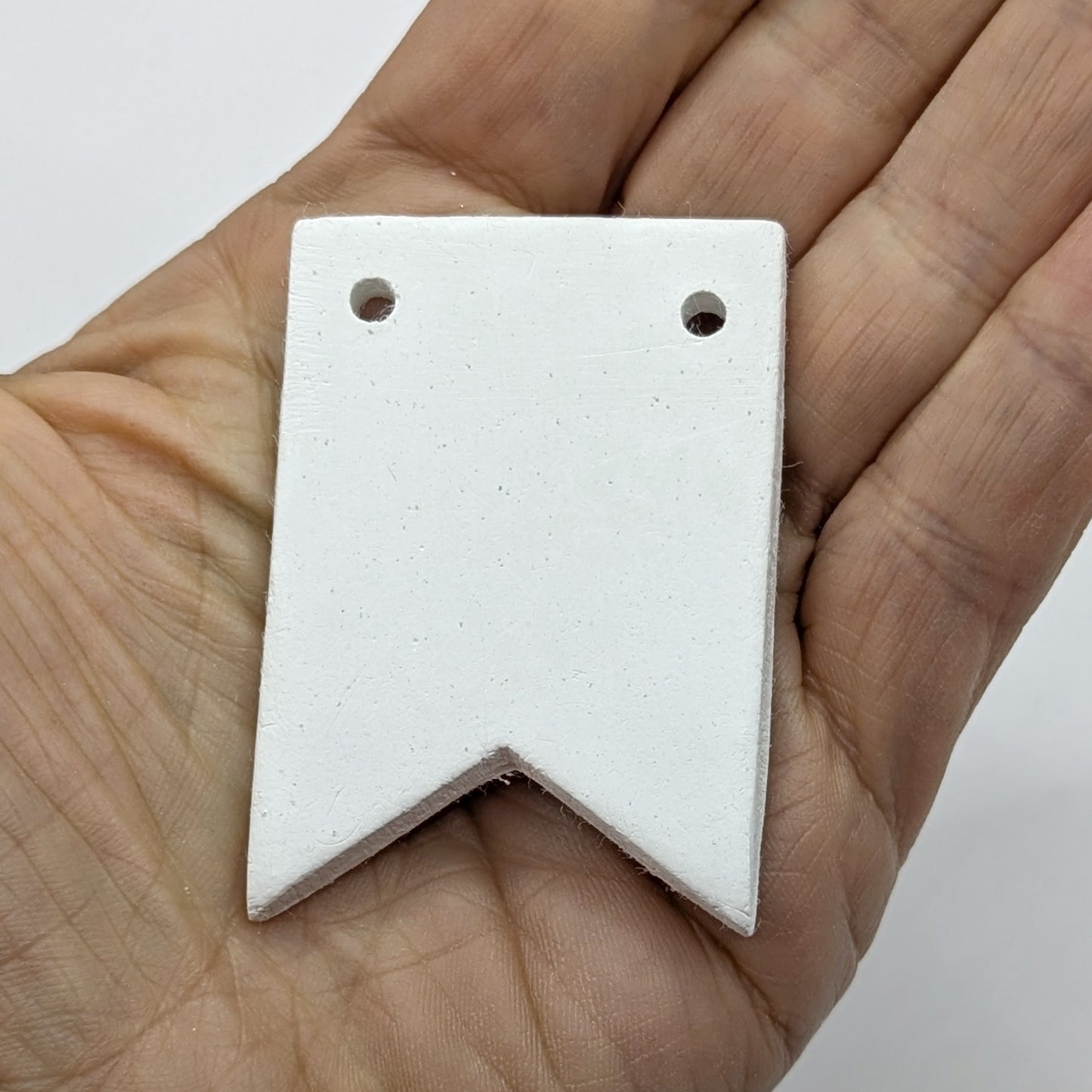 white air dried clay in the shape of bunting, shown in palm of hand 