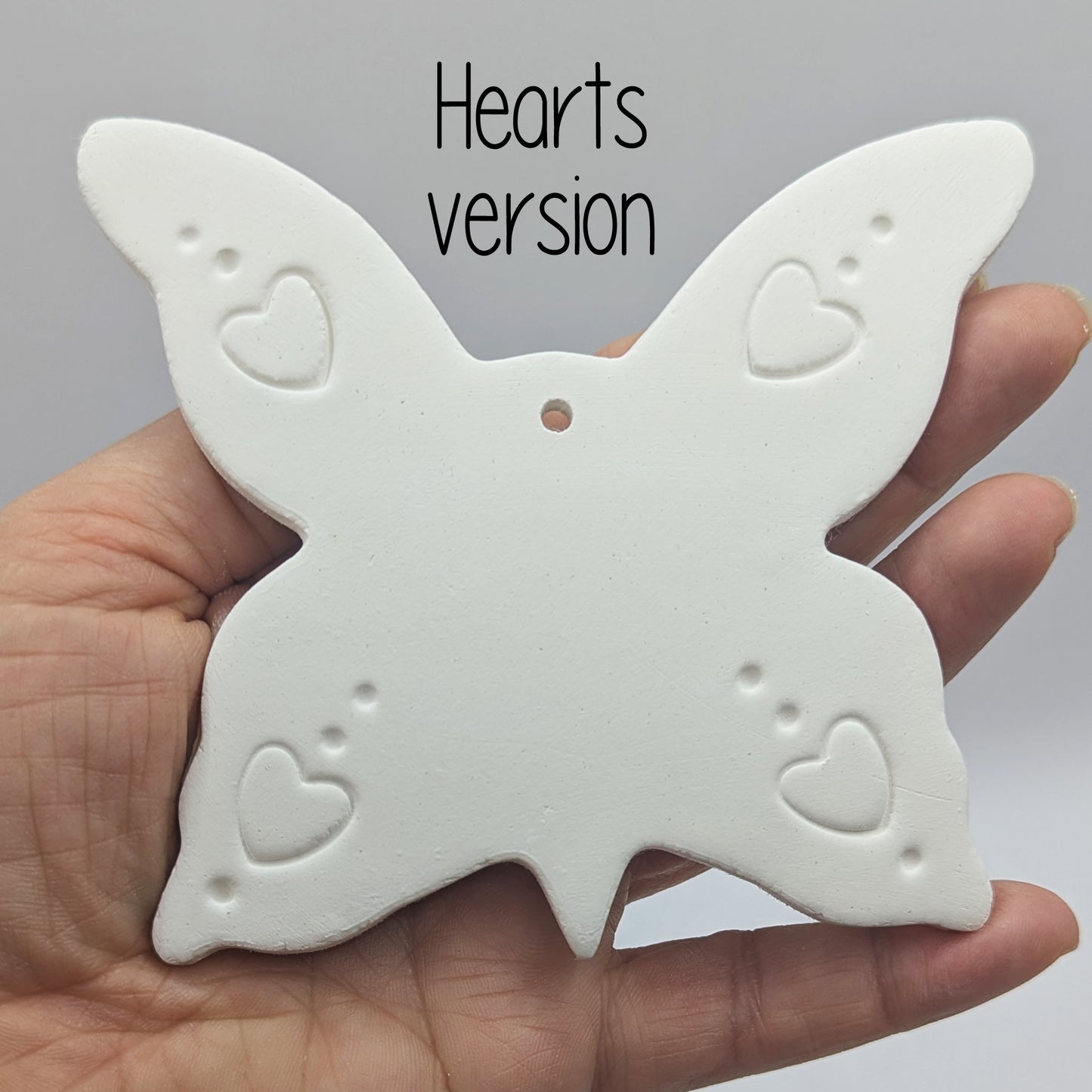 large clay butterfly decoration in a ladies hand to show scale, with a heart pattern stamped into the wings
