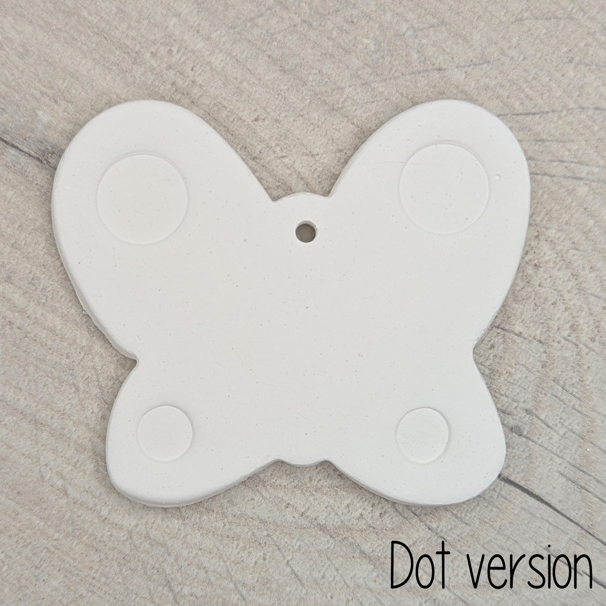 small air dried clay butterfly decoration, with a dotted pattern stamped into the wings