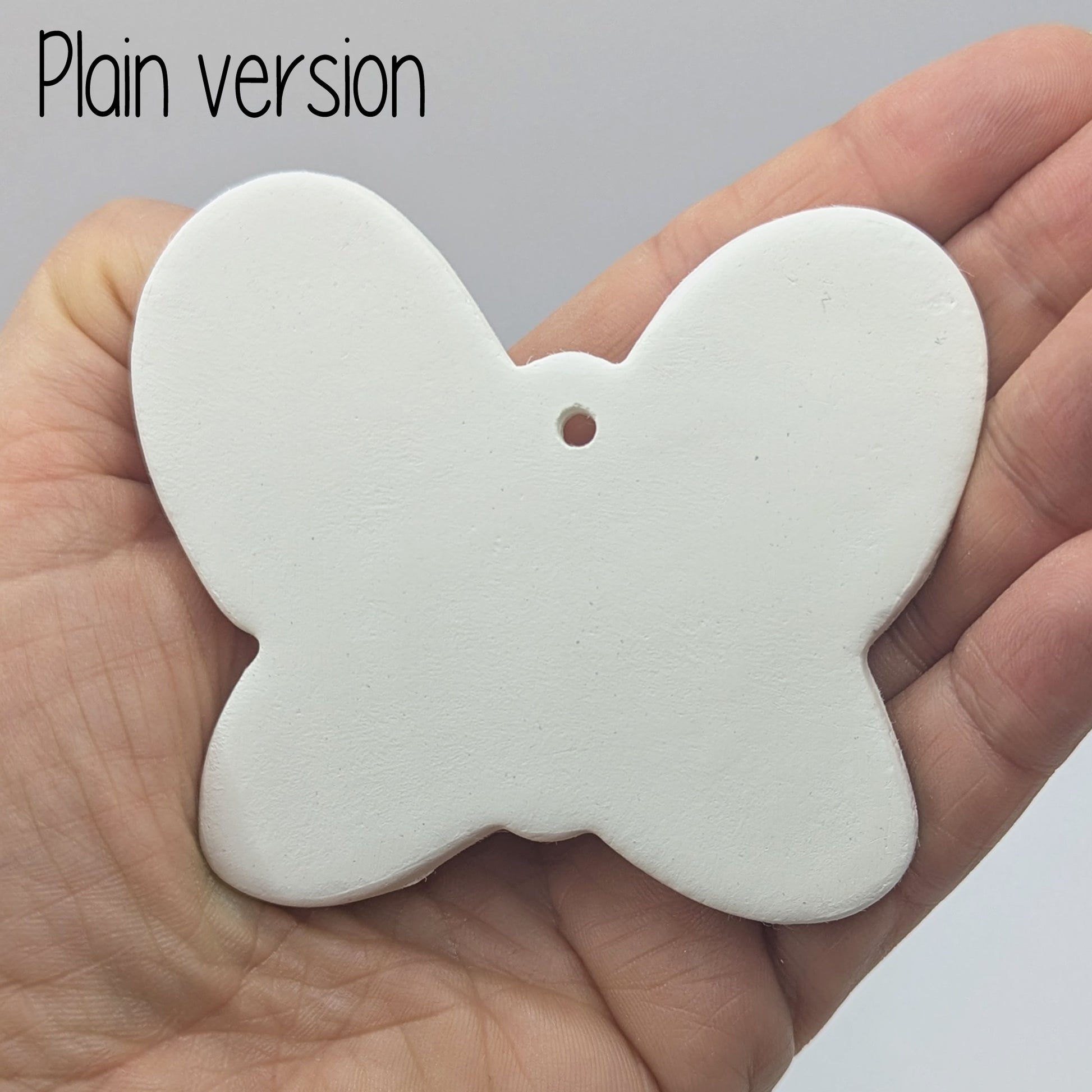 small plain air dried clay butterfly decoration, in a ladies hand to show scale