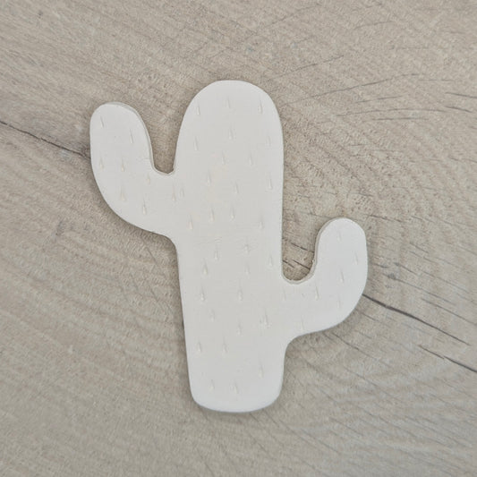 cactus shaped clay decoration, with spike details stamped in on a light wooden background