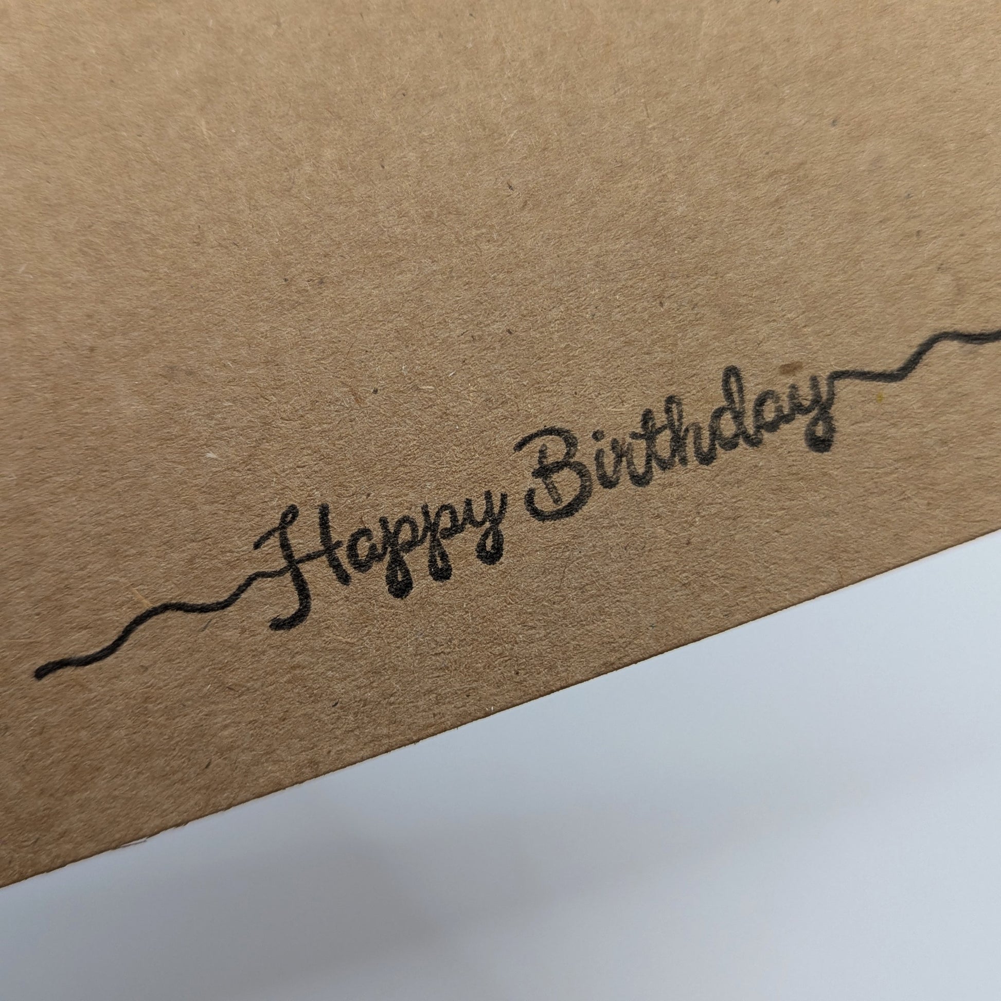 happy birthday stamped in black ink onto a kraft card