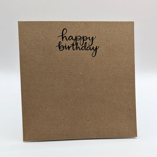 happy birthday stamped onto a kraft card in black ink