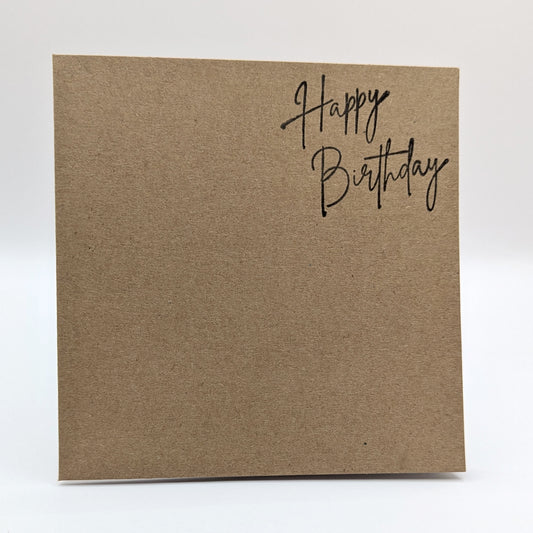 happy birthday stamped onto the top right corner of a kraft card in black in