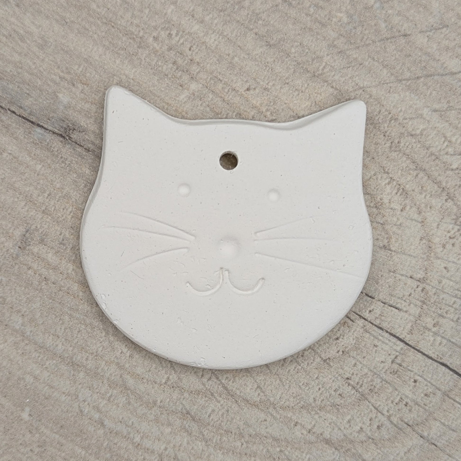 small cute cat face shaped clay decoration with a cat face stamped into it to paint and decorate