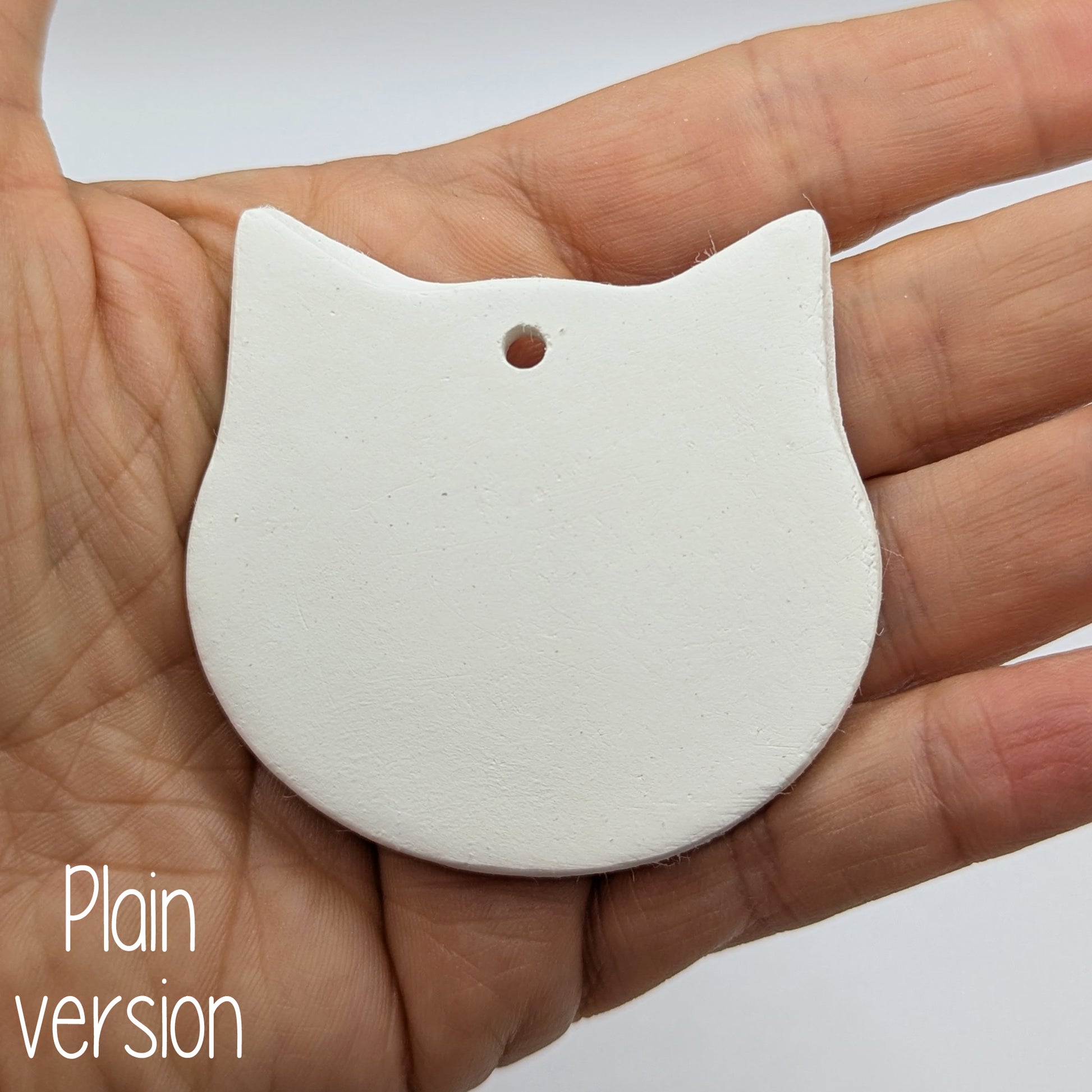 small cat face shaped decoration in some ones hand to show size