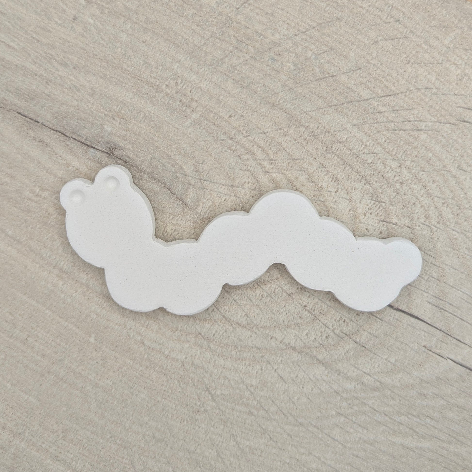 caterpiller clay decoration on a light wood background
