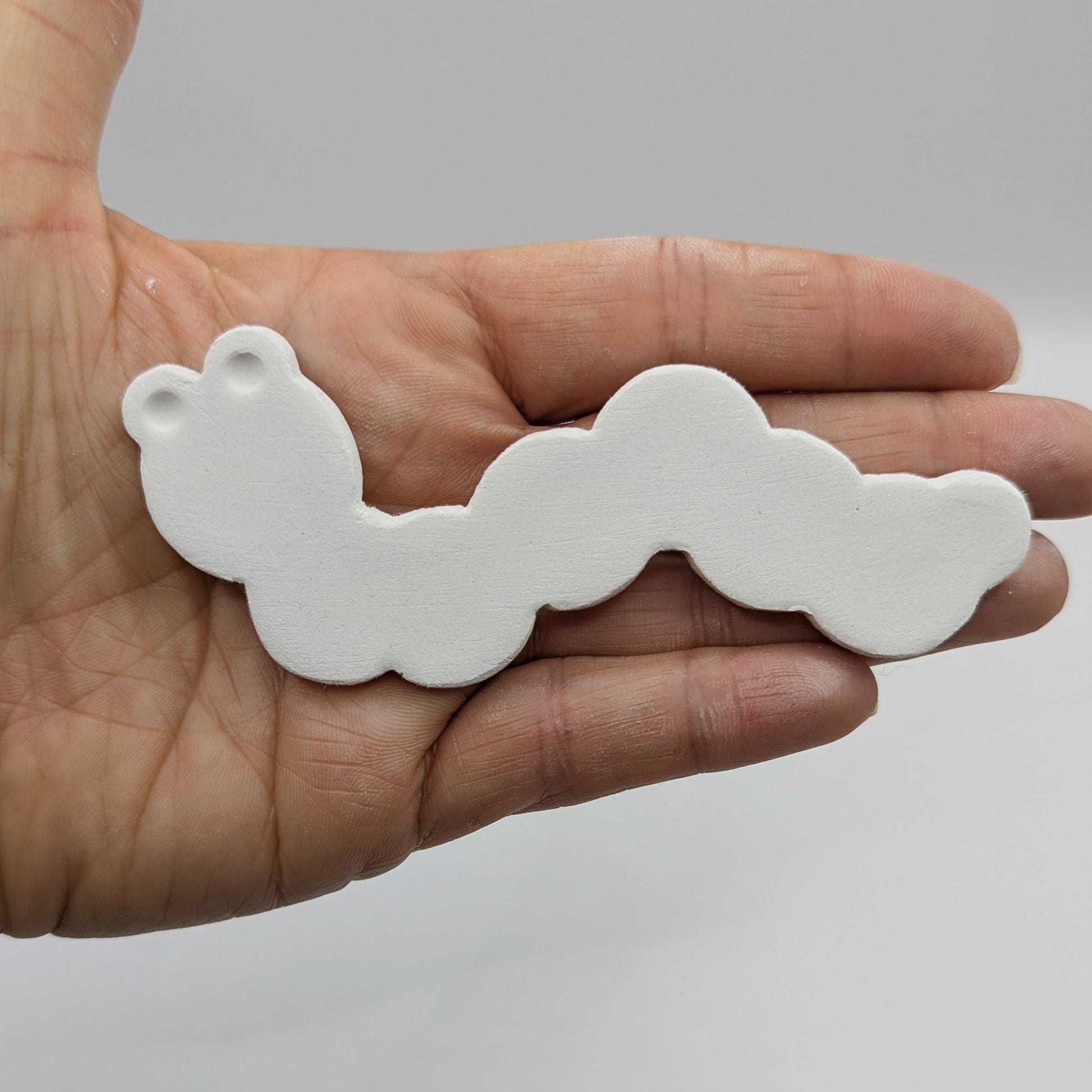 caterpillar clay decoration held in a hand for scale