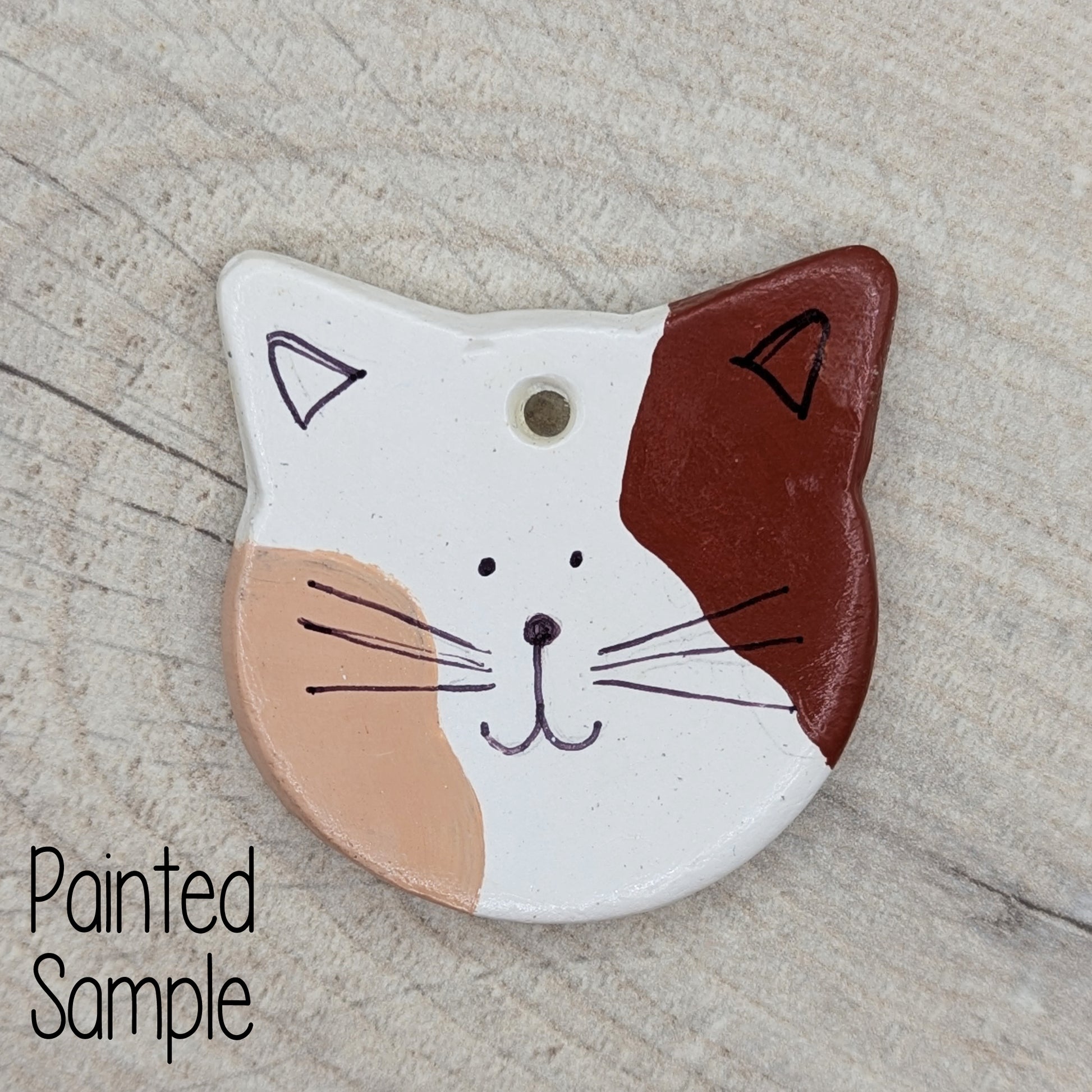 small cat face decoration painted in shades of brown to look like a family pet cat