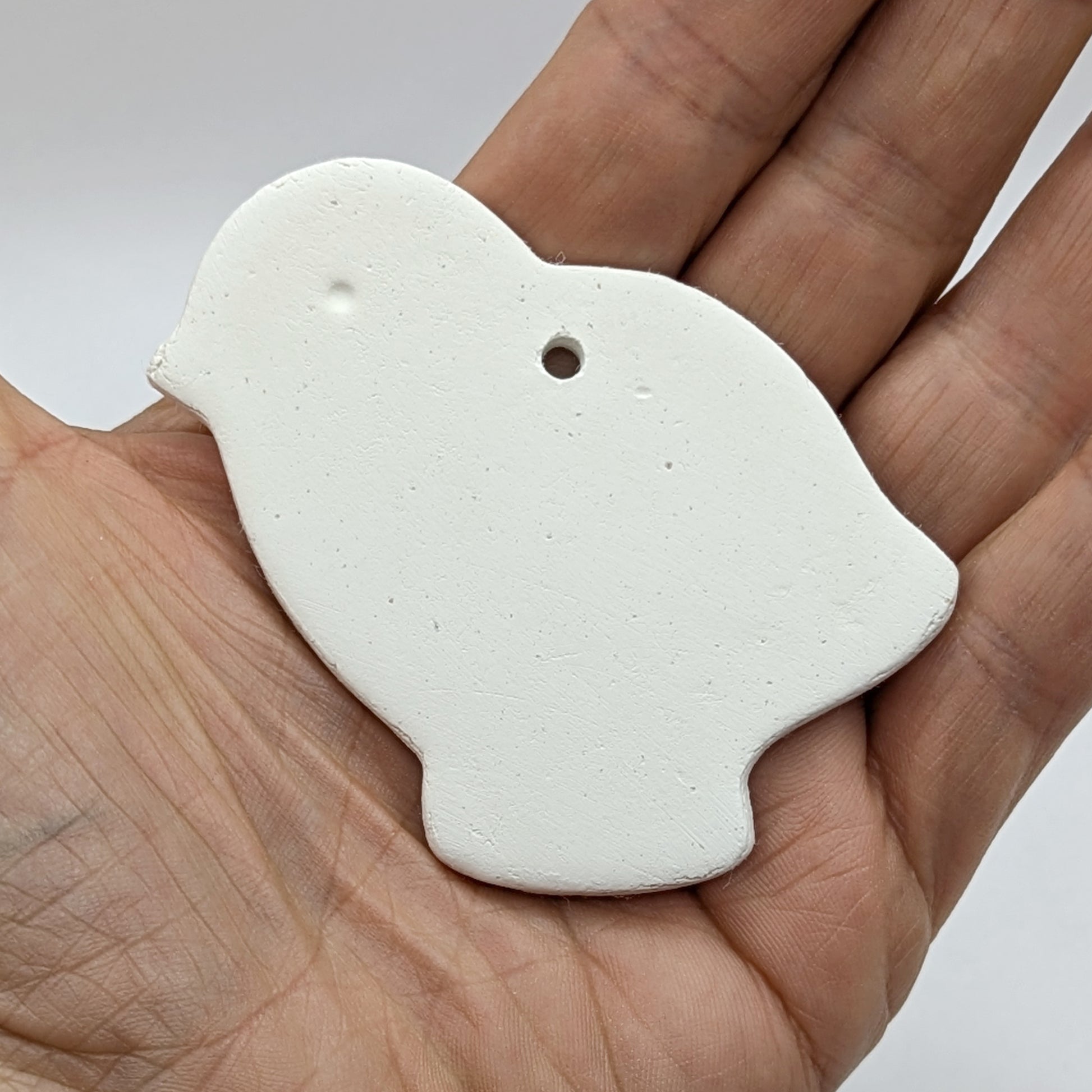 small chick air dried clay decoration shown on palm of hand