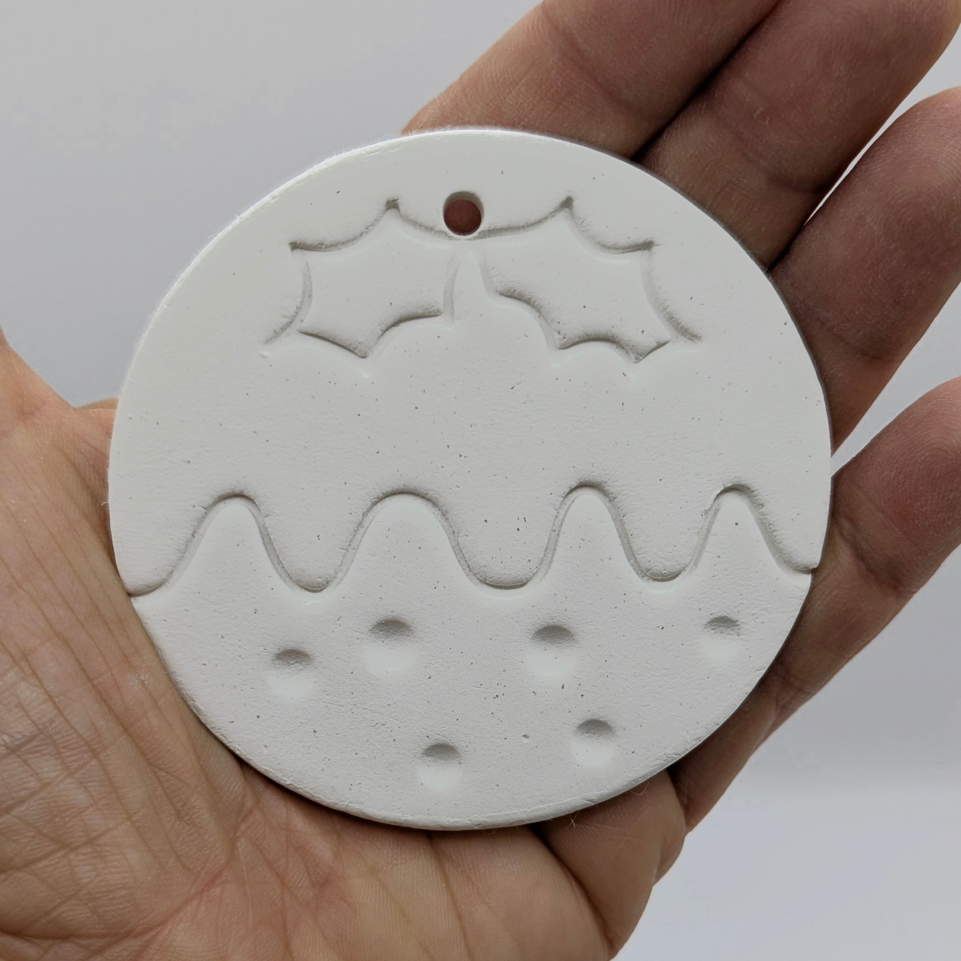 round christmas pudding shaped clay decoration to paint yourself held in some ones hand to show scale