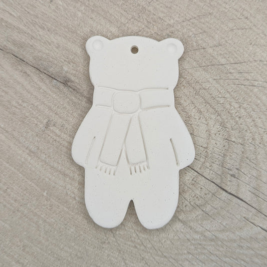 white air dried clay teddy bear ornament with a scarf stamped on, on a wooden surface